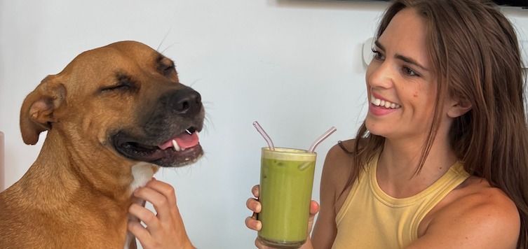 a girl sharing her smoothie with her dog