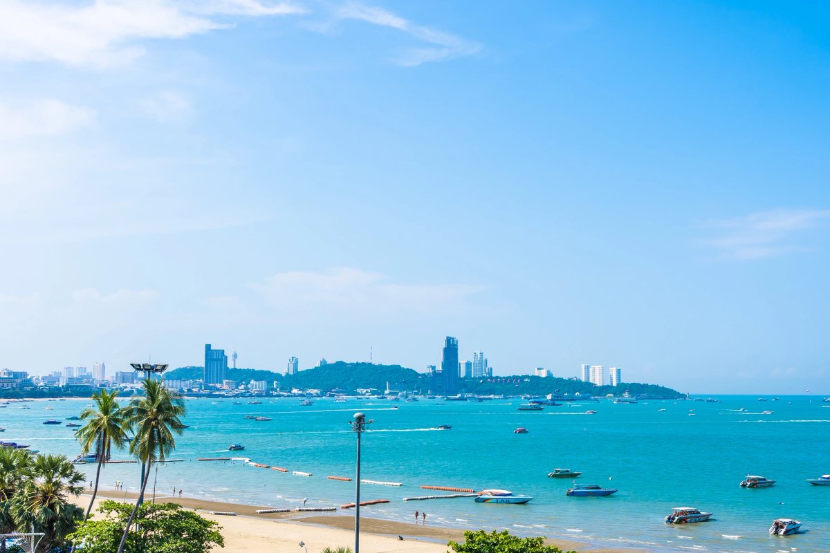Bangkok city skyline beside a tropical Thai beach with longtail boats