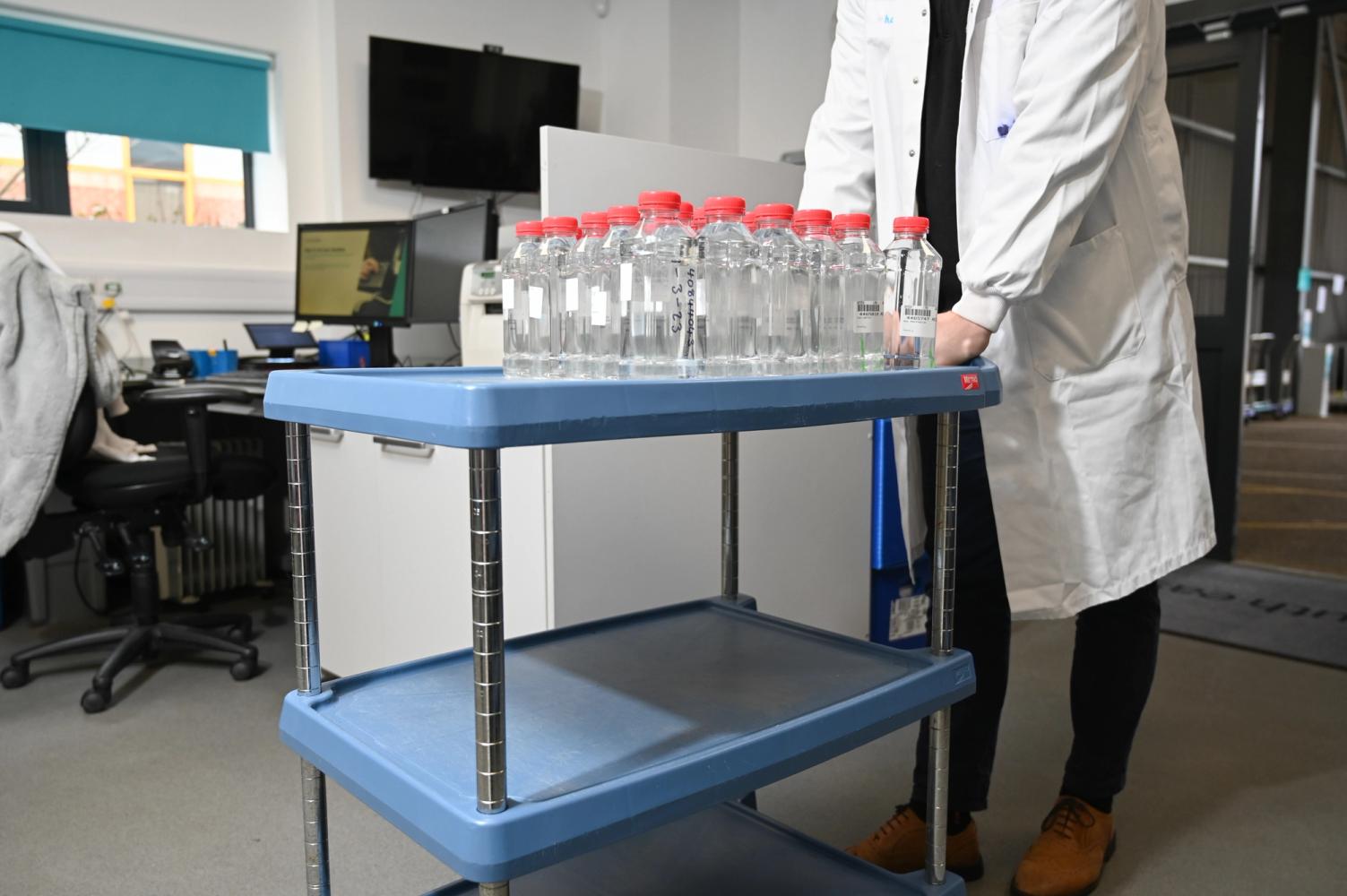 photograph of a technician wheeling a trolley of water samples through the laboratory