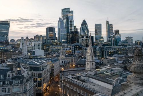 A panoramic view of London's skyline featuring a mix of modern skyscrapers and historic buildings at dusk. The image captures the contrast between the contemporary architecture and the classic structures below, showcasing the city’s dynamic urban landscape.