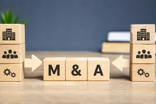 The image features wooden blocks arranged on a desk, prominently displaying the letters 'M & A' at the center, symbolizing mergers and acquisitions. Flanking the central blocks are icons representing companies and teamwork, underscoring the collaborative nature of business takeovers.