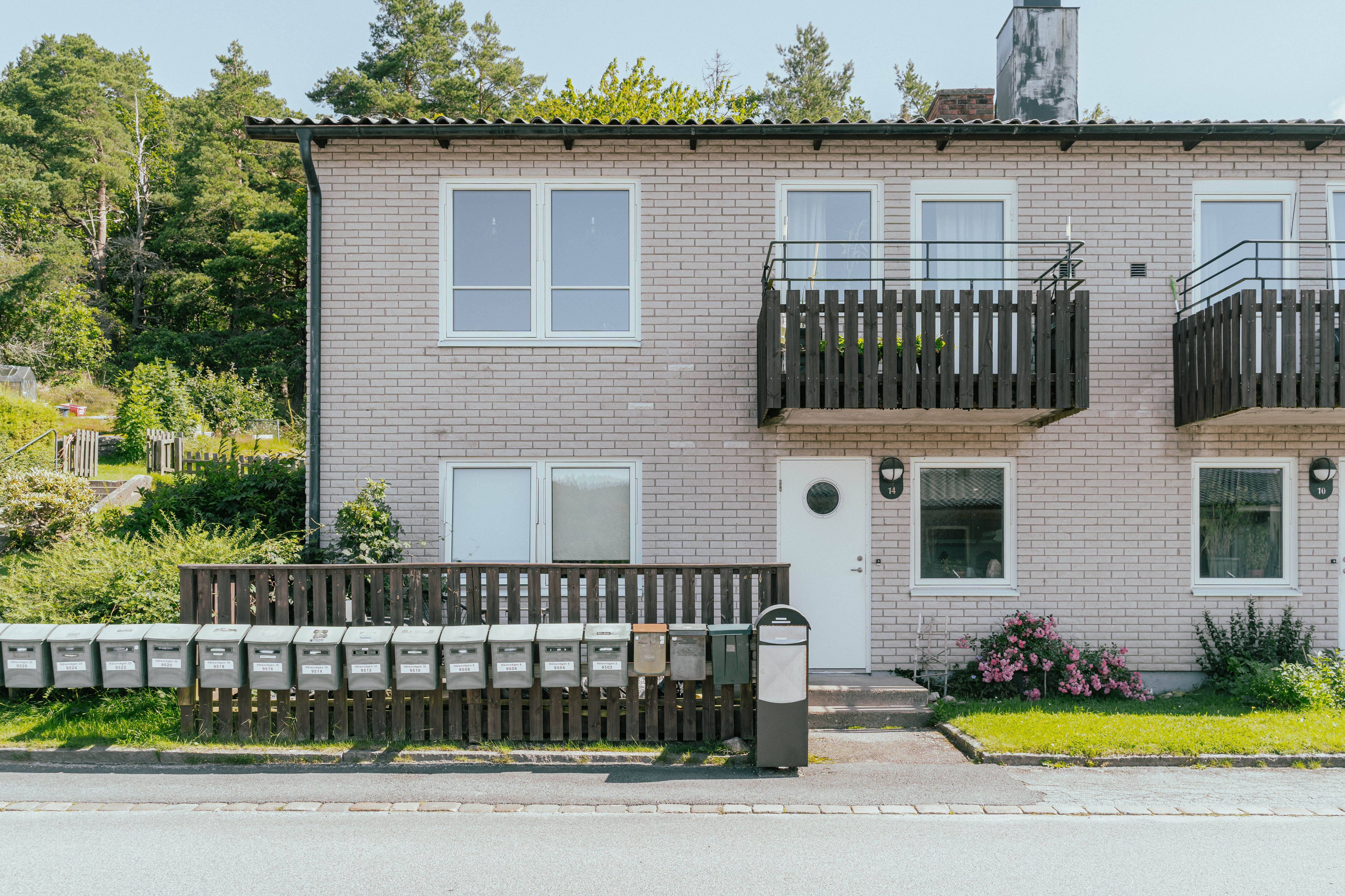 Fasaden av ett  tvåvåningshus med många brevlådor framför
