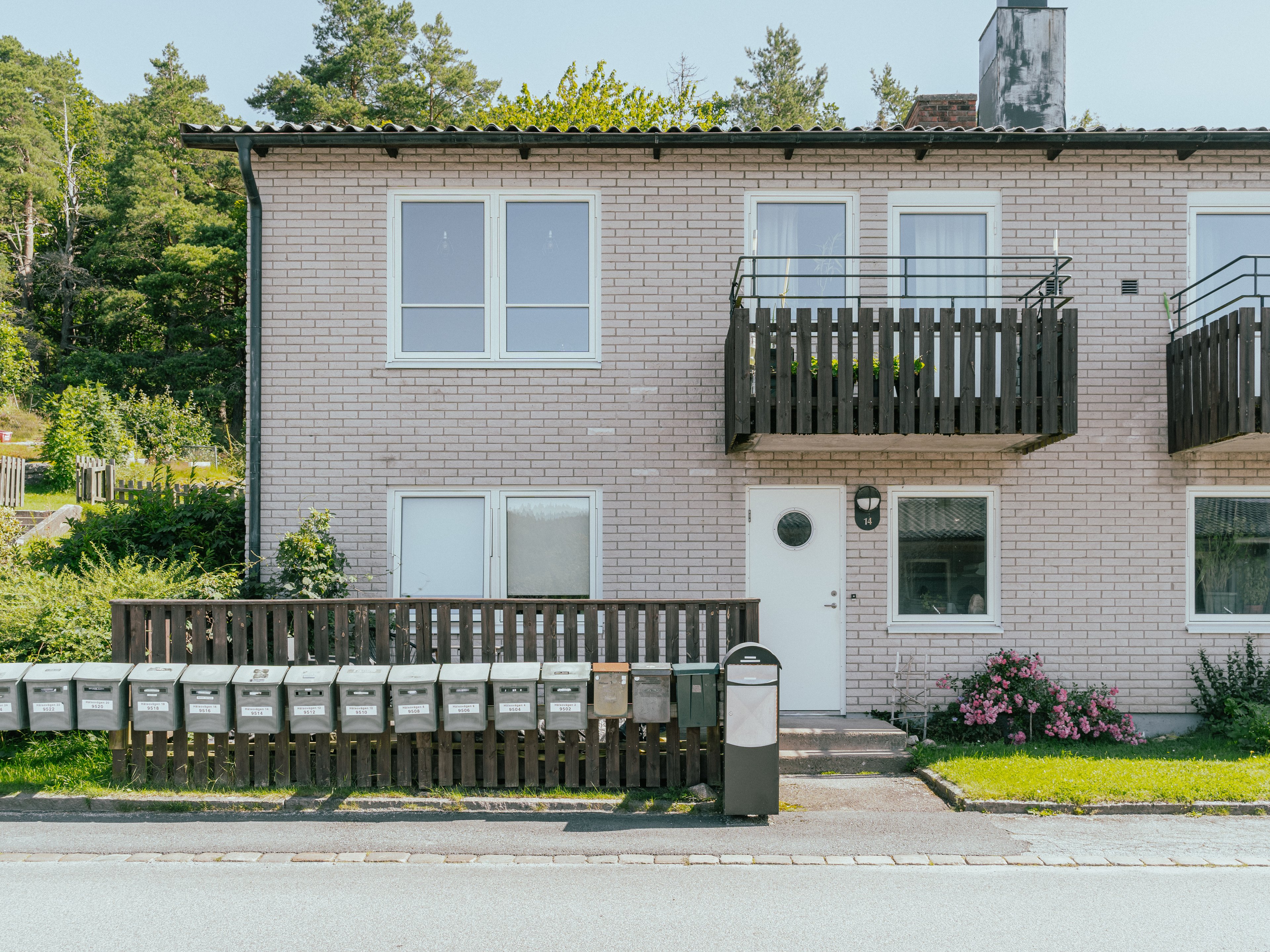 Fasaden av ett tvåvåningshus med många brevlådor framför