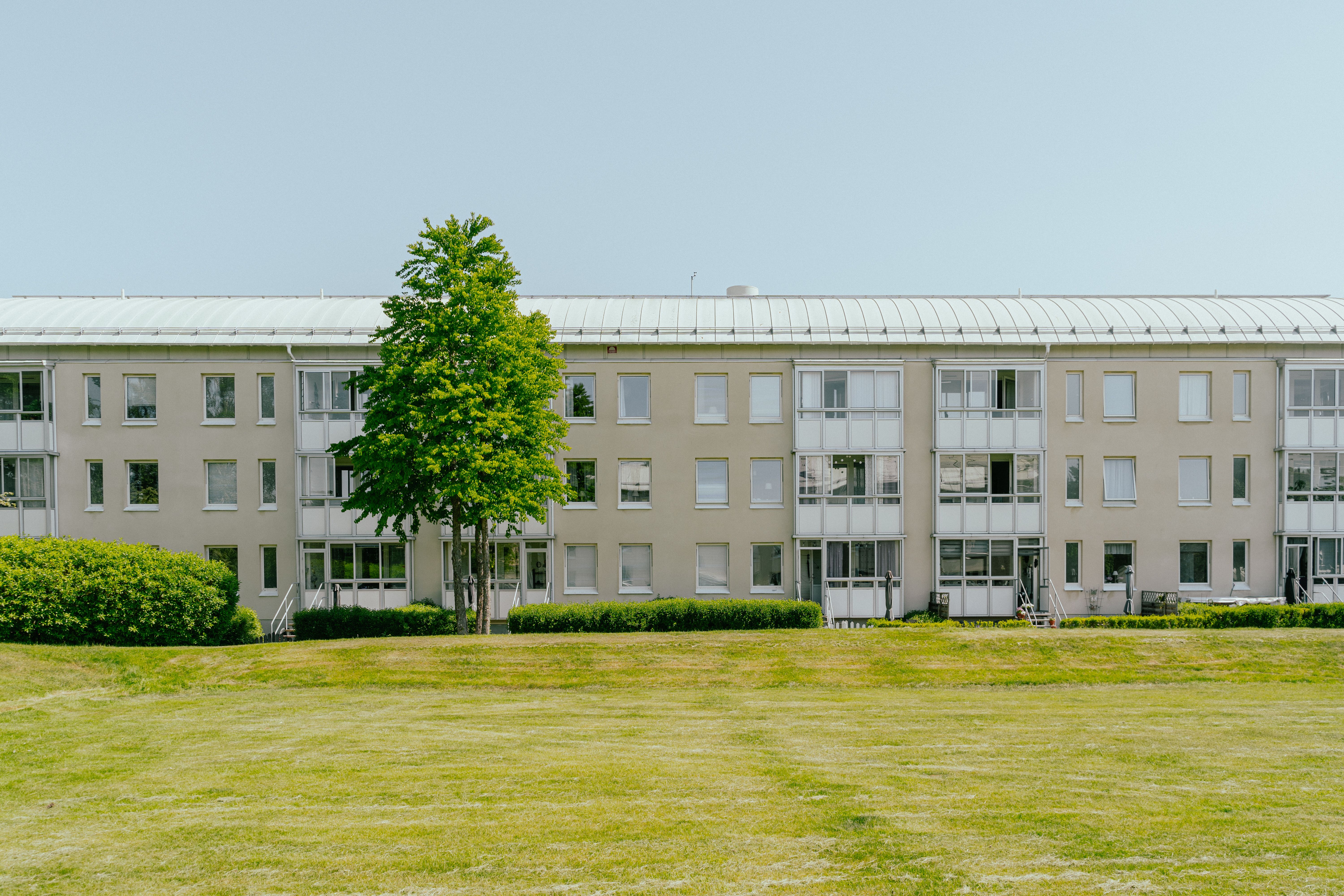 En lång huslänga med en stor gräsmatta framför