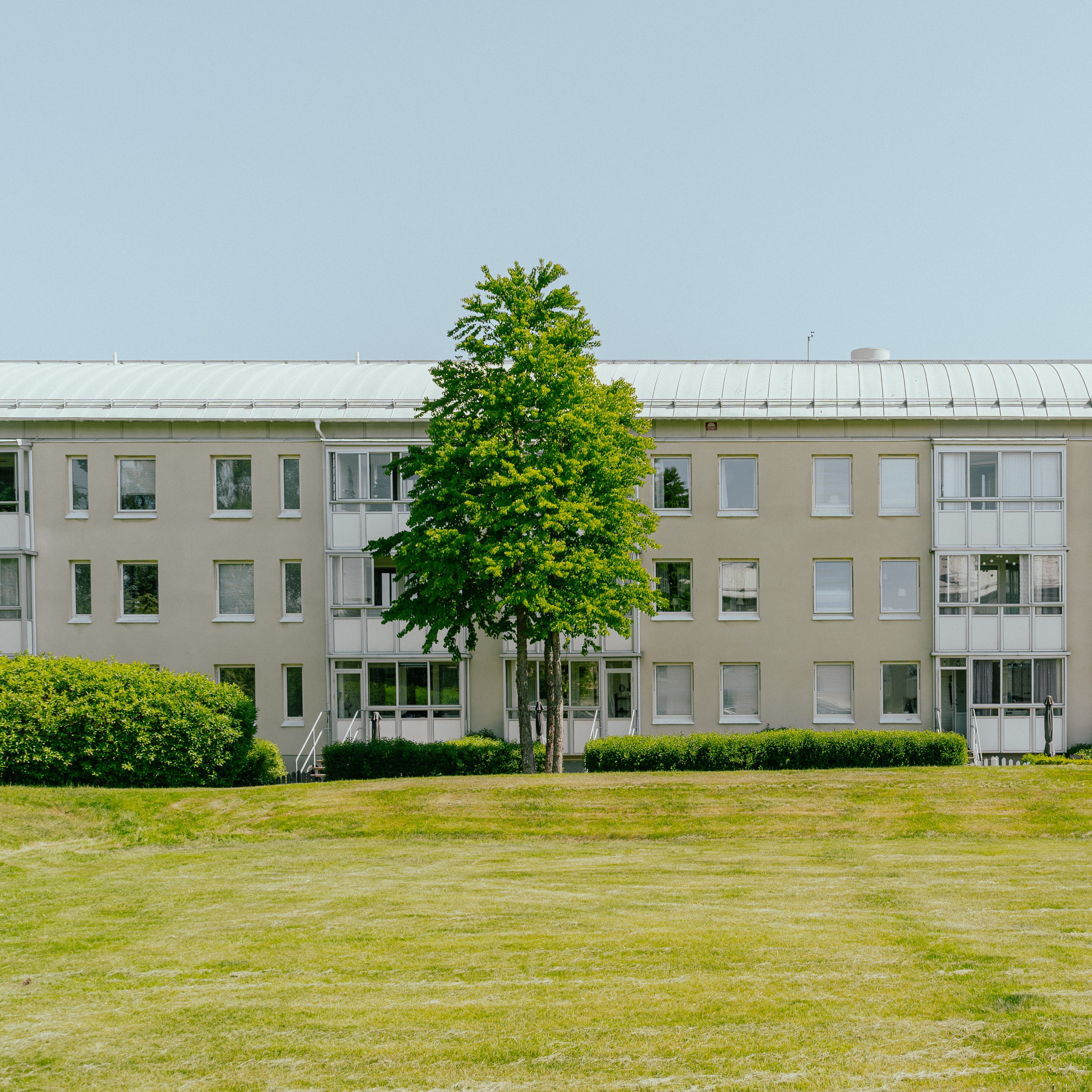 En lång huslänga med en stor gräsmatta framför