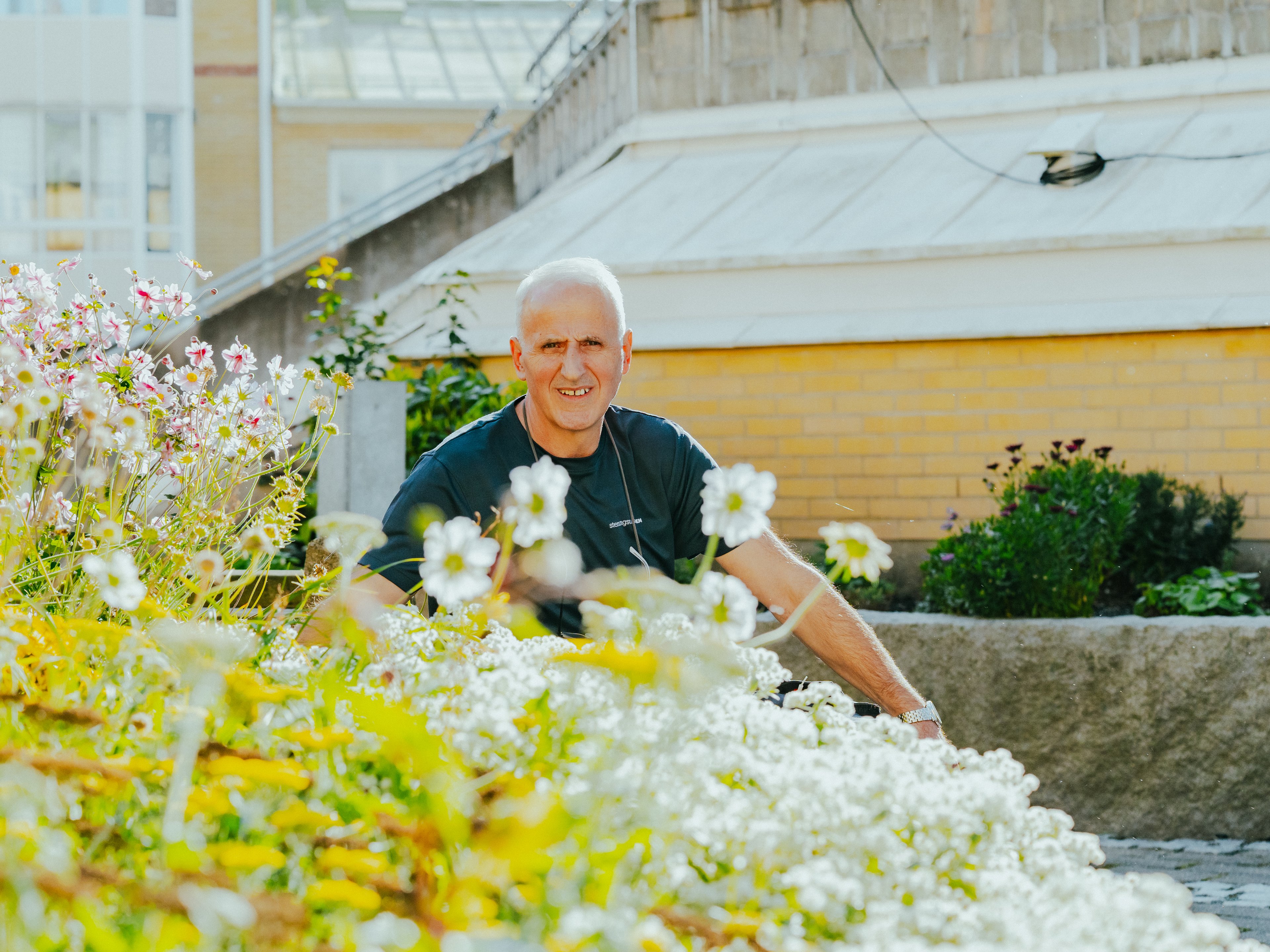 En man sitter omgiven av blommor