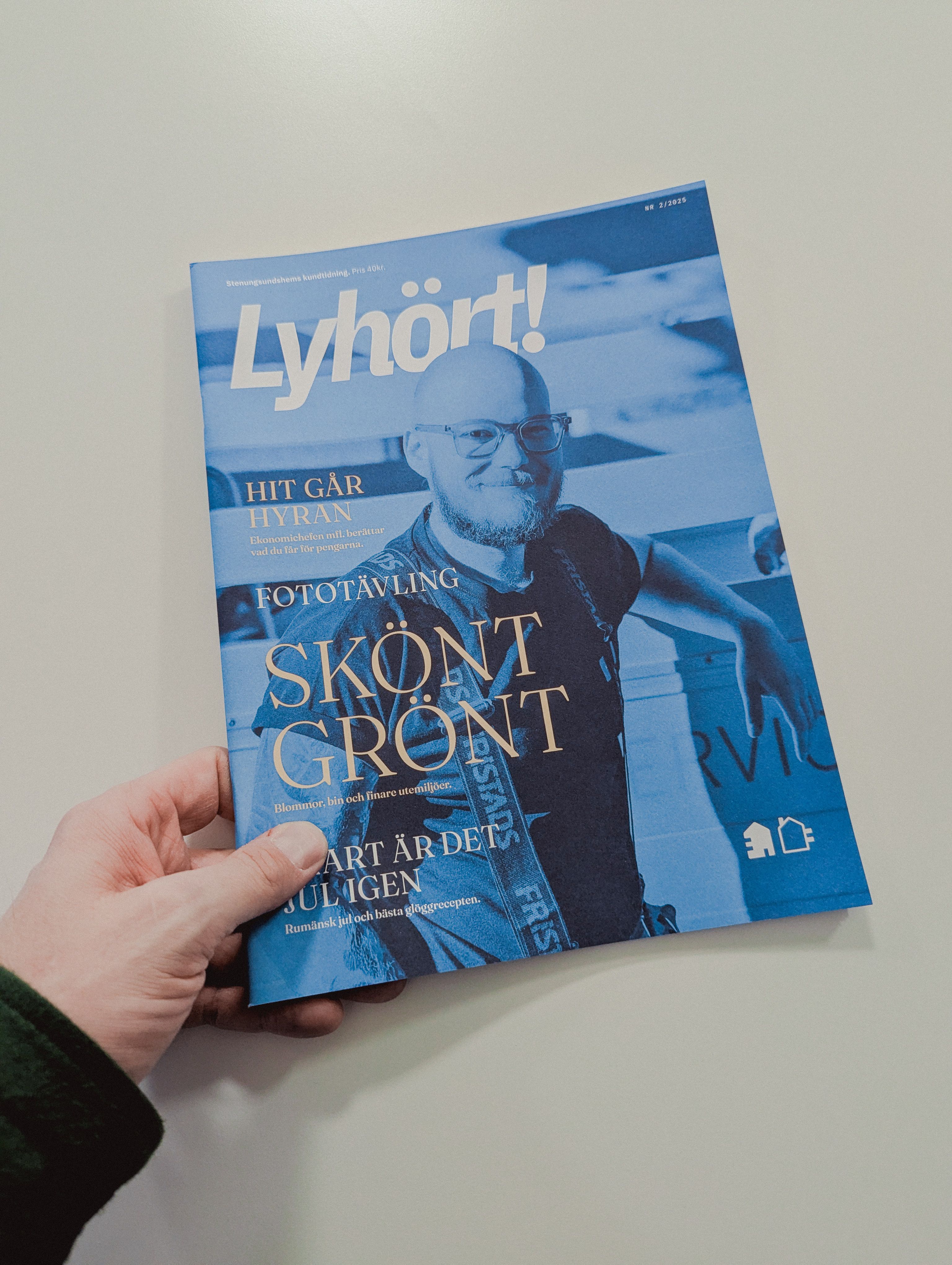 En hand håller i en framsidan på kundtidningen Lyhört