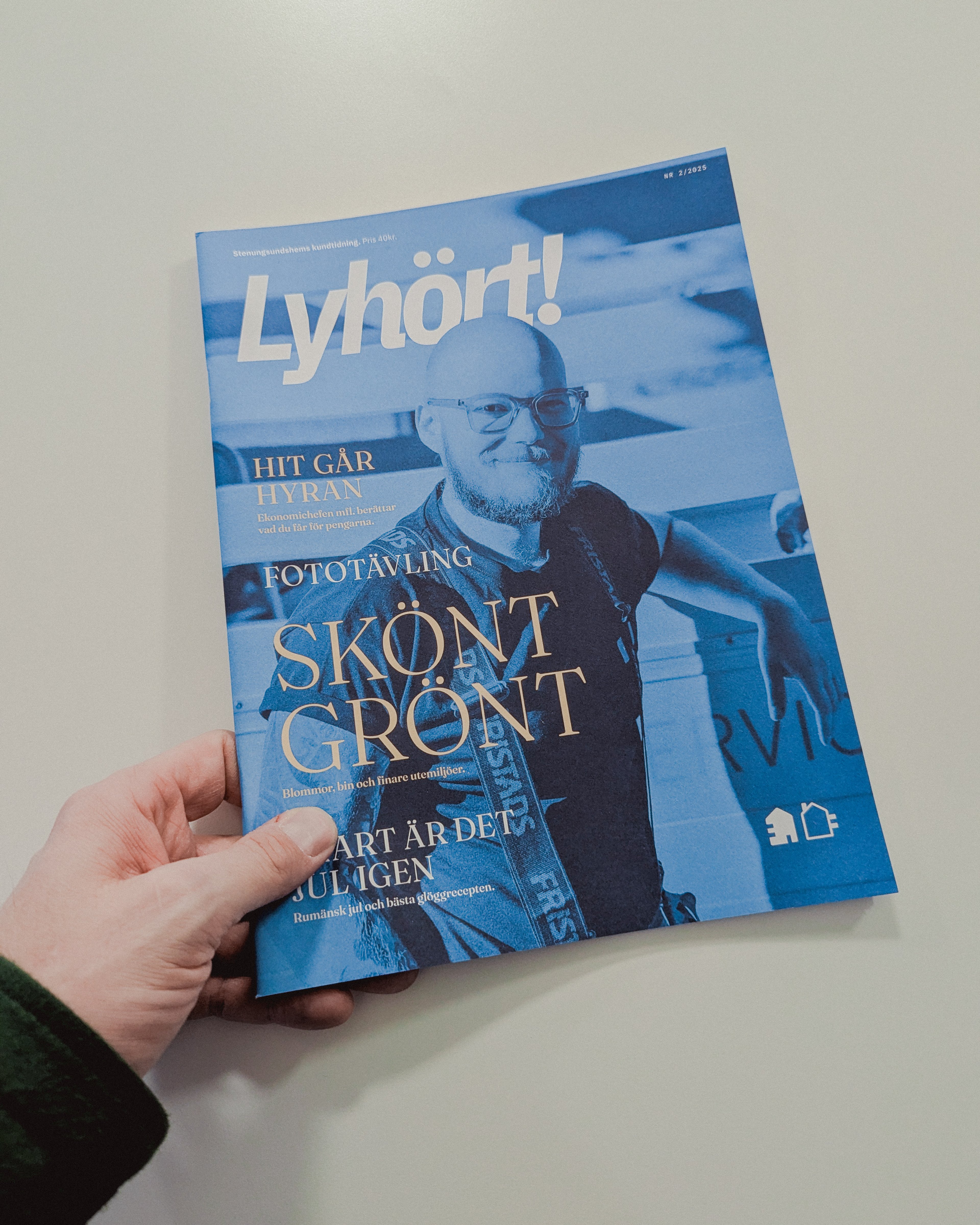 En hand håller i en framsidan på kundtidningen Lyhört