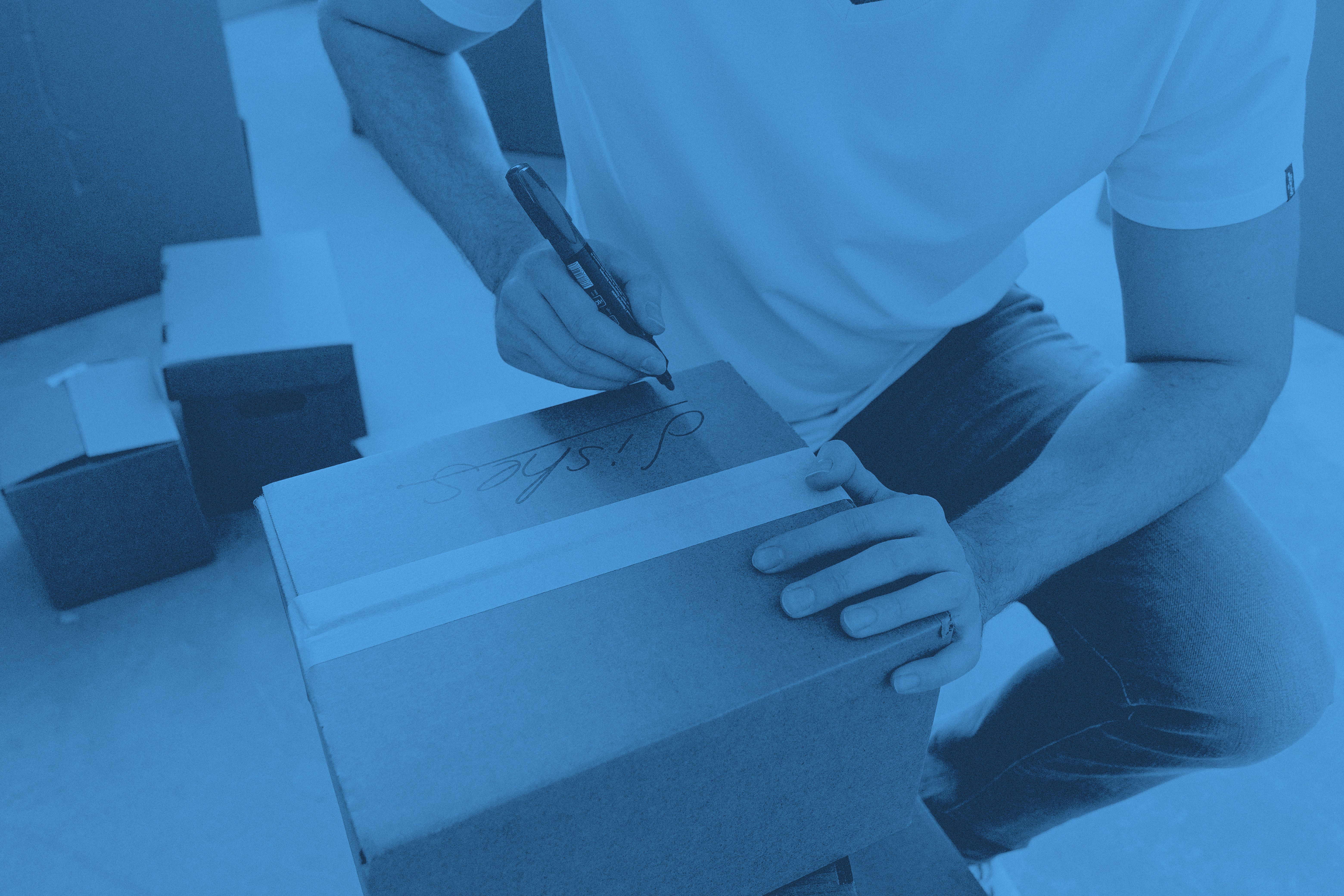 En person skriver något på en flyttkartong