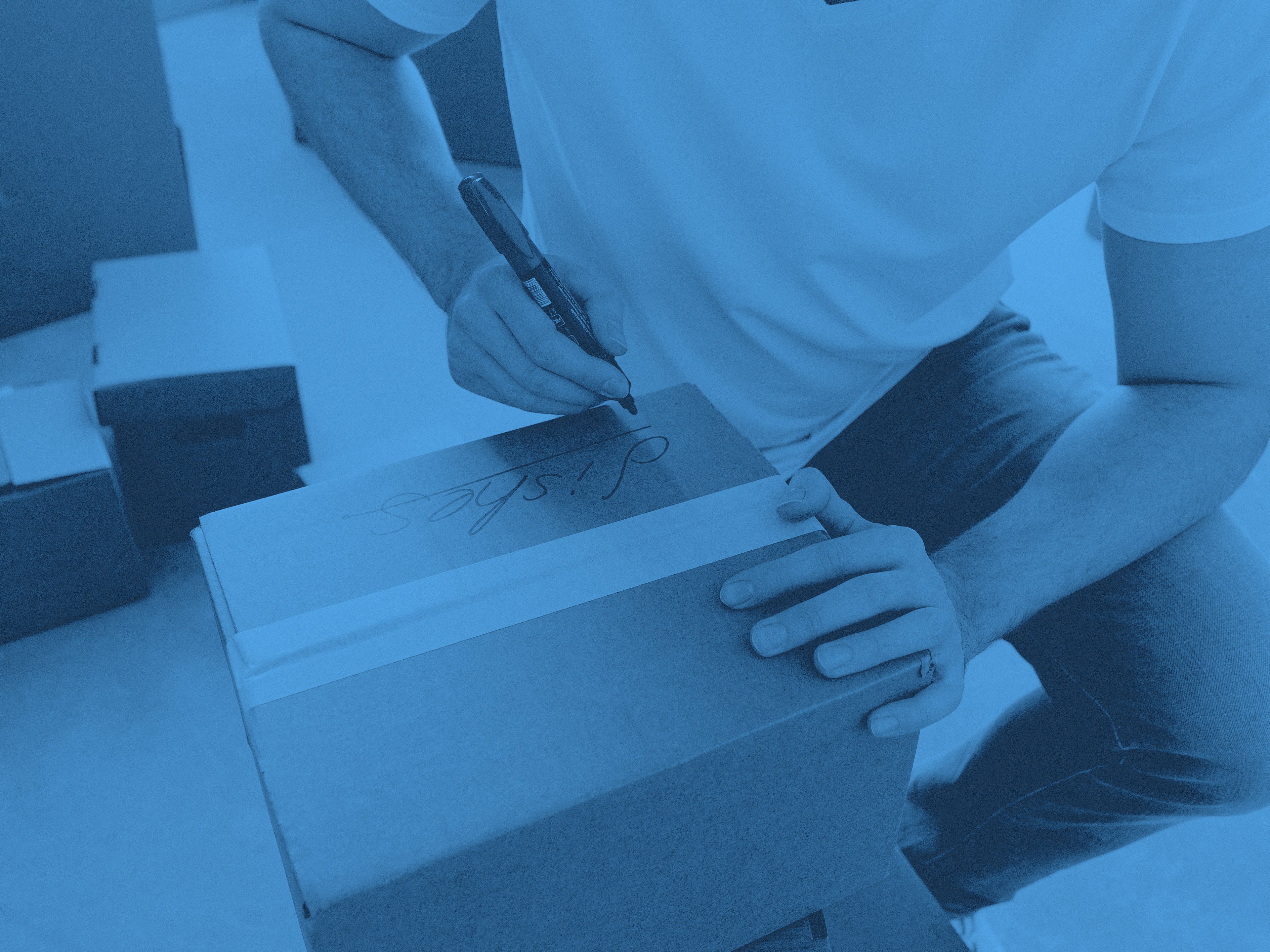 En person skriver något på en flyttkartong