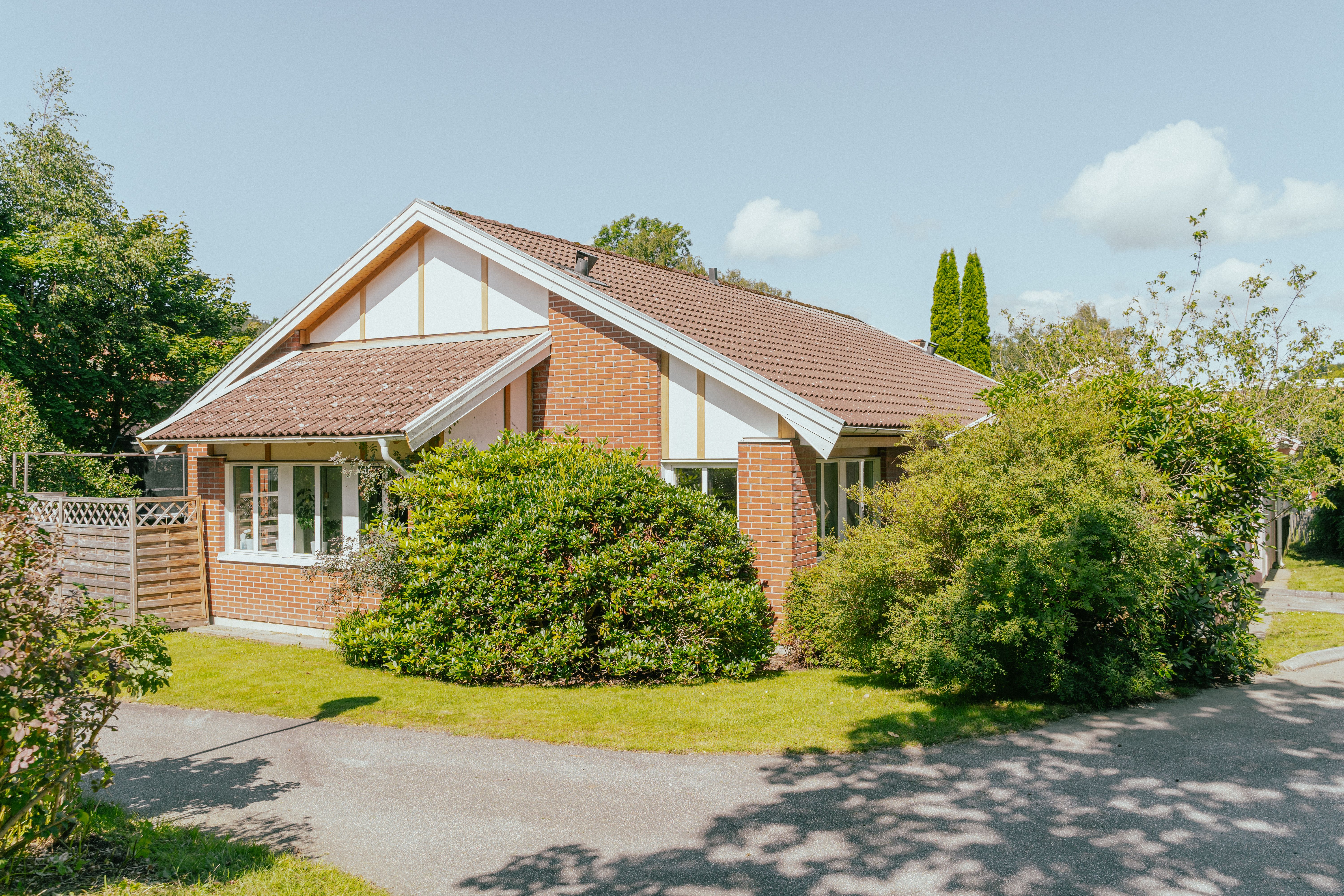 Ett enplanshus med tegelfasad samt buskage