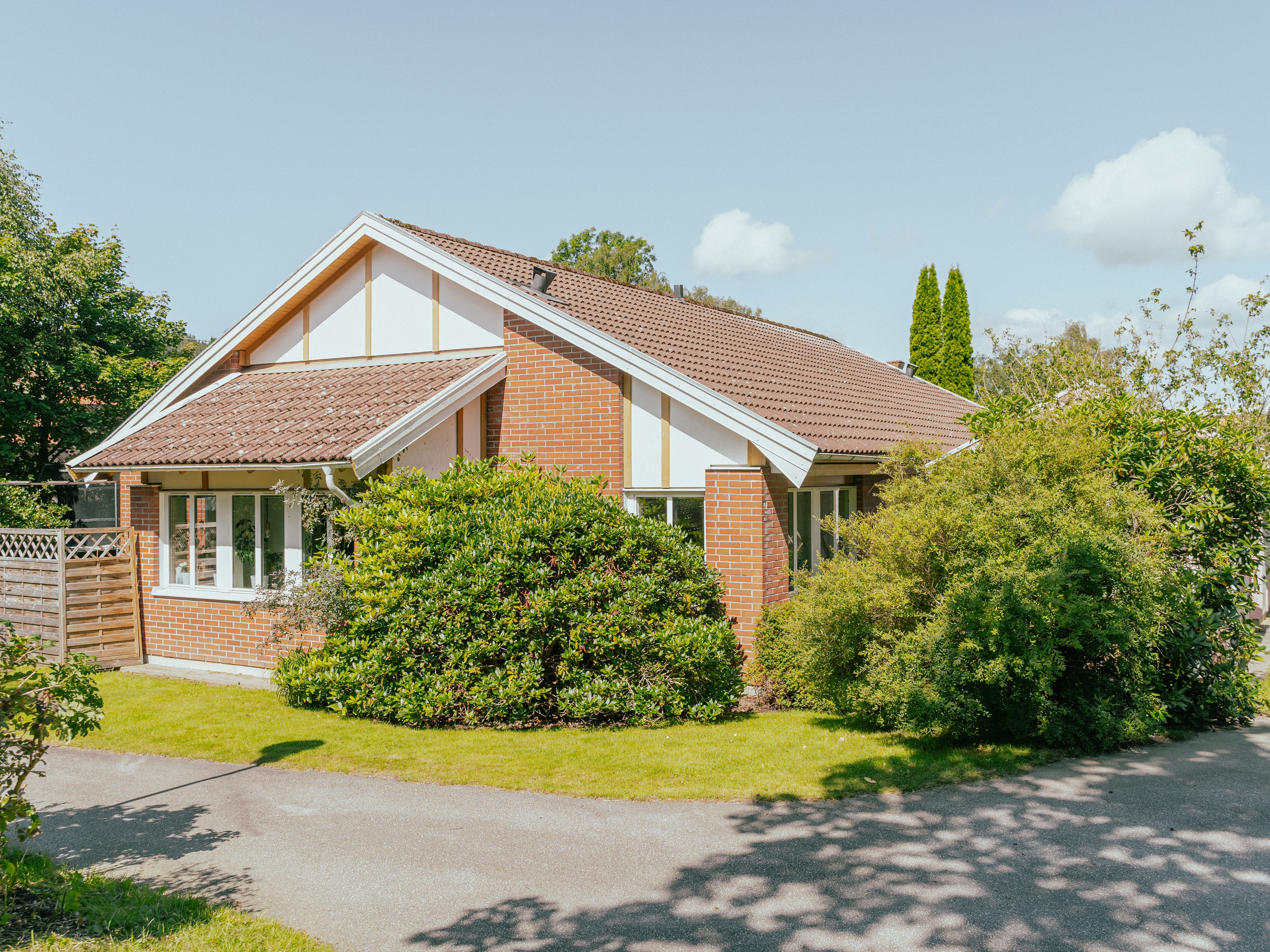 Ett enplanshus med tegelfasad samt buskage
