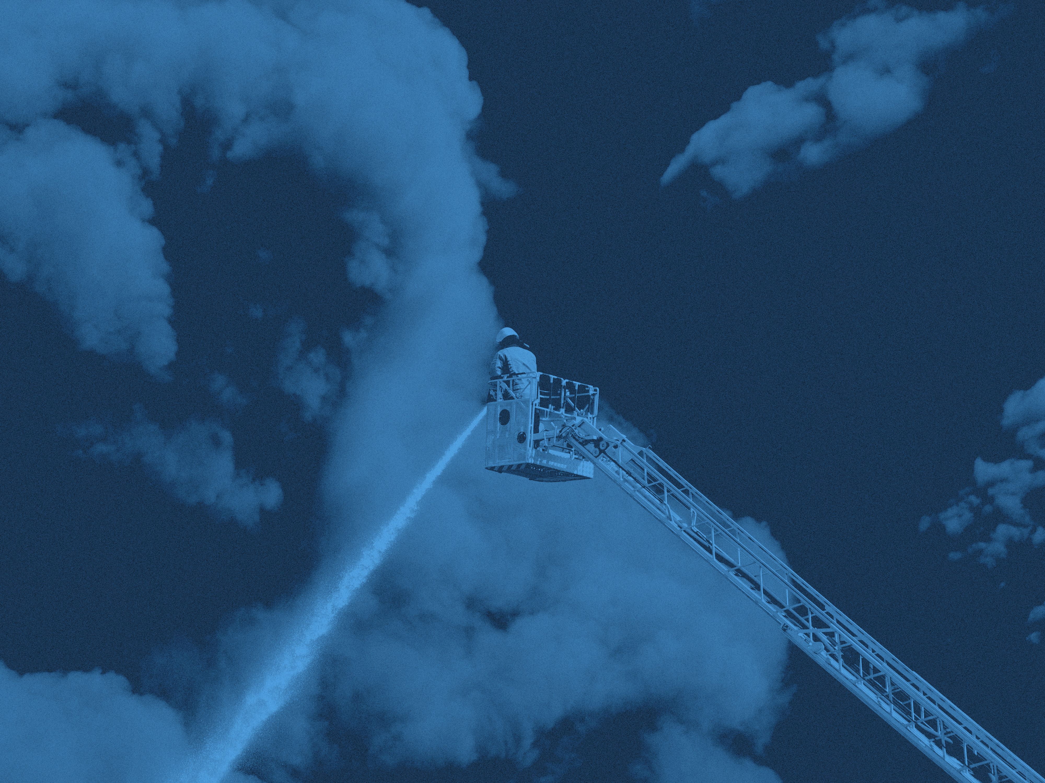 En brandman på stege som sprutar vatten