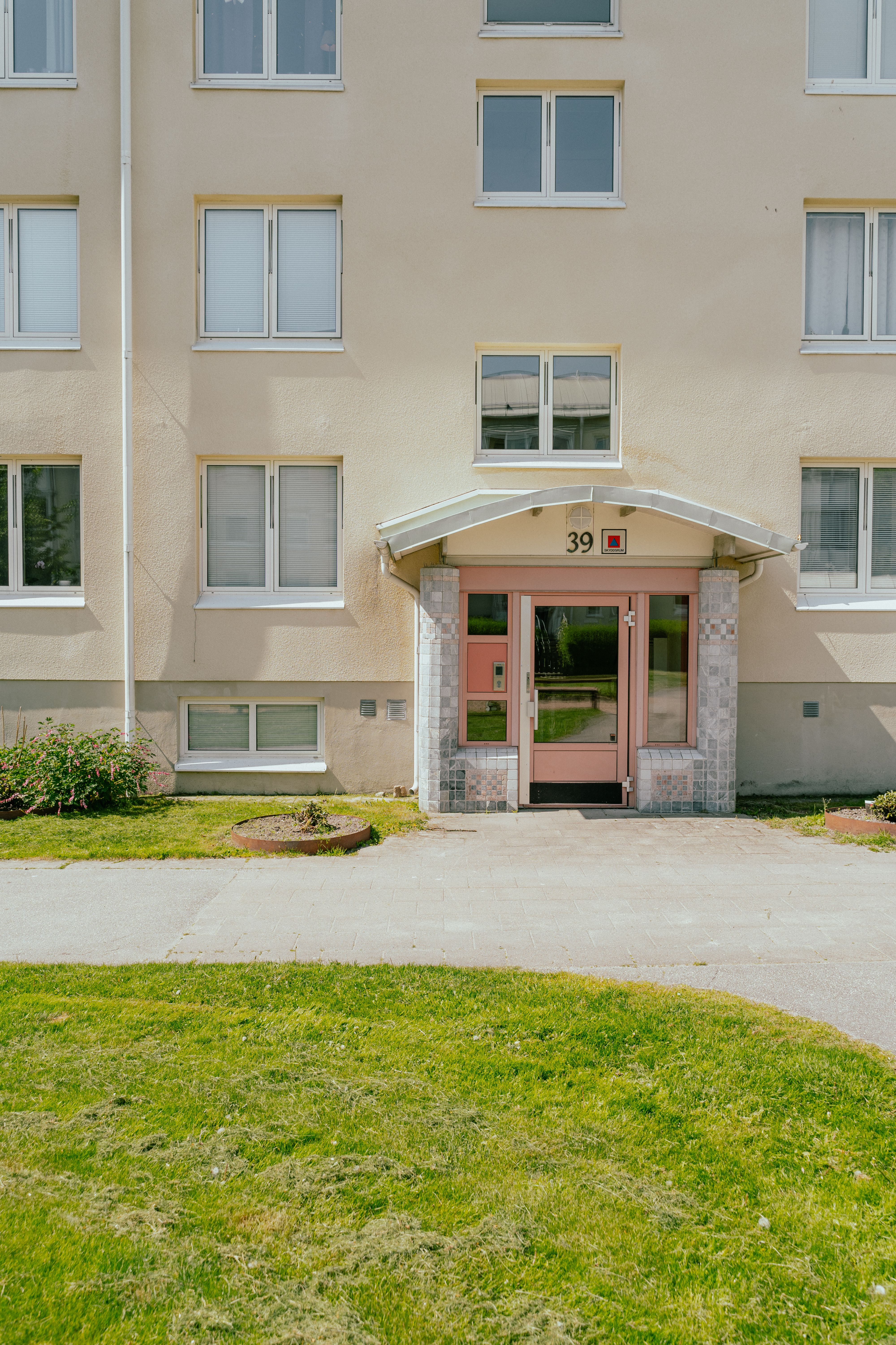 En entré till ett flervåningshus med gräsmatta framför