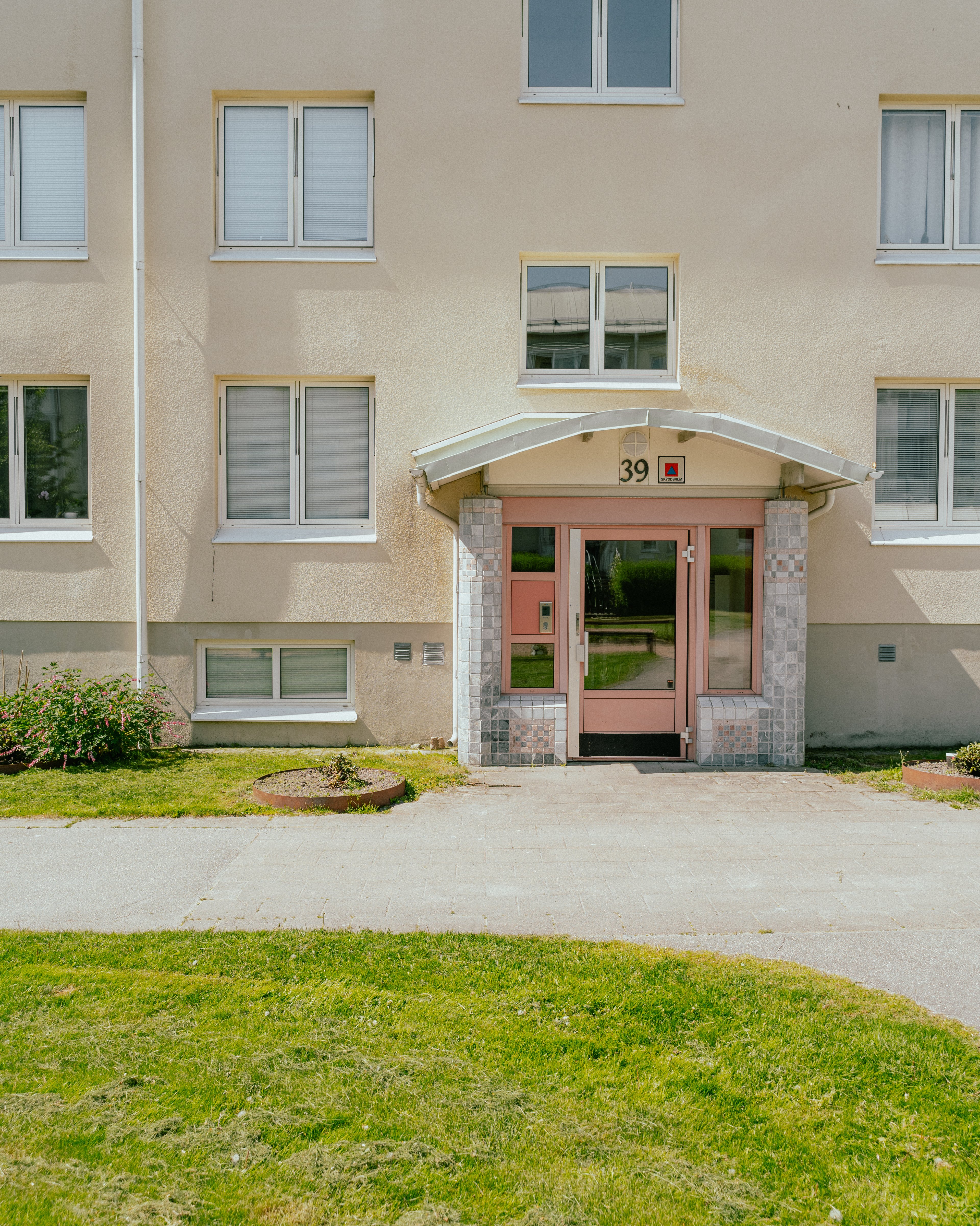 En entré till ett flervåningshus med gräsmatta framför