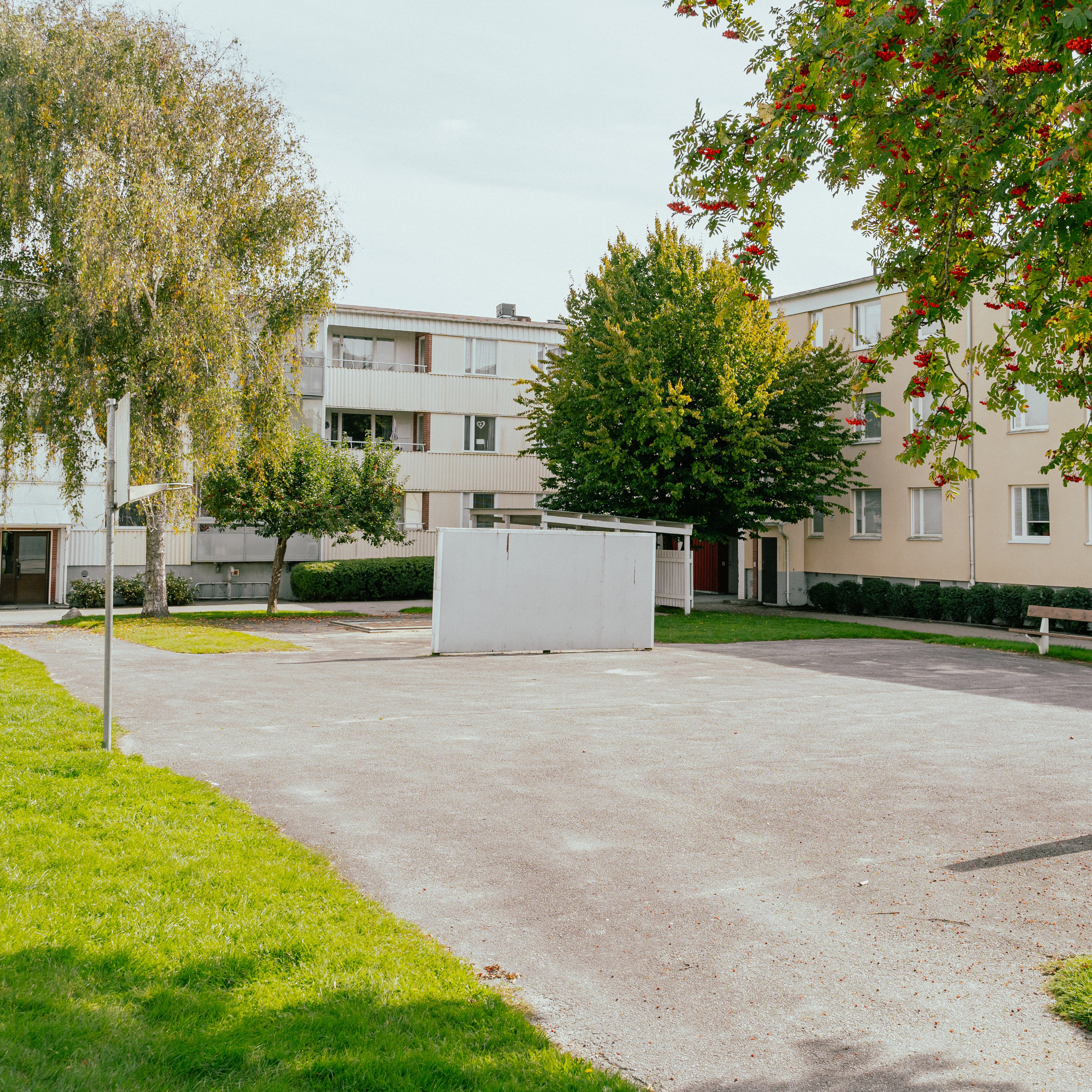 En asfalterad fotbollsplan i mitten av en stor gård