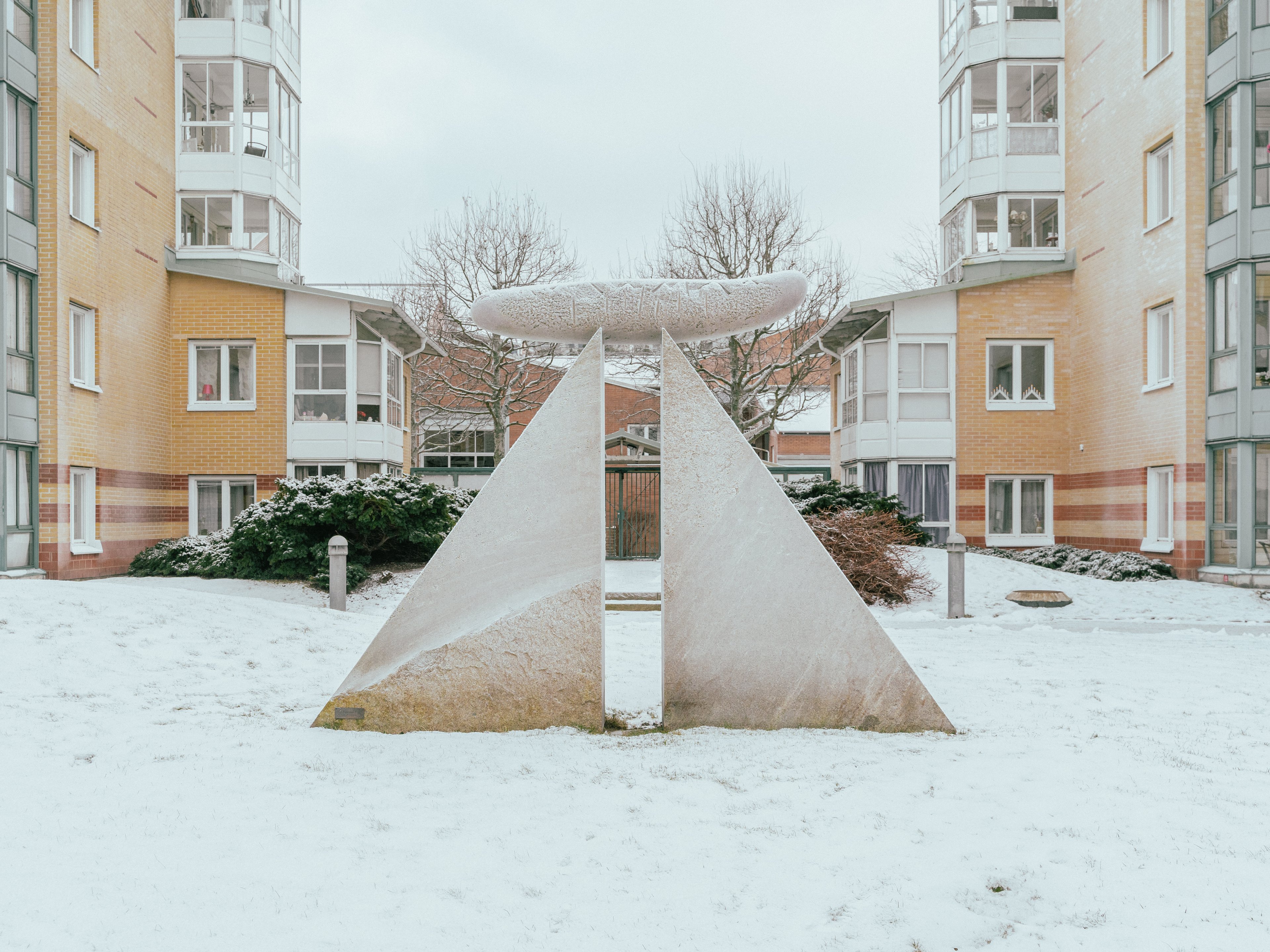 Ett konstverk i granit med två trekantiga stenblock med en cylinder på toppen