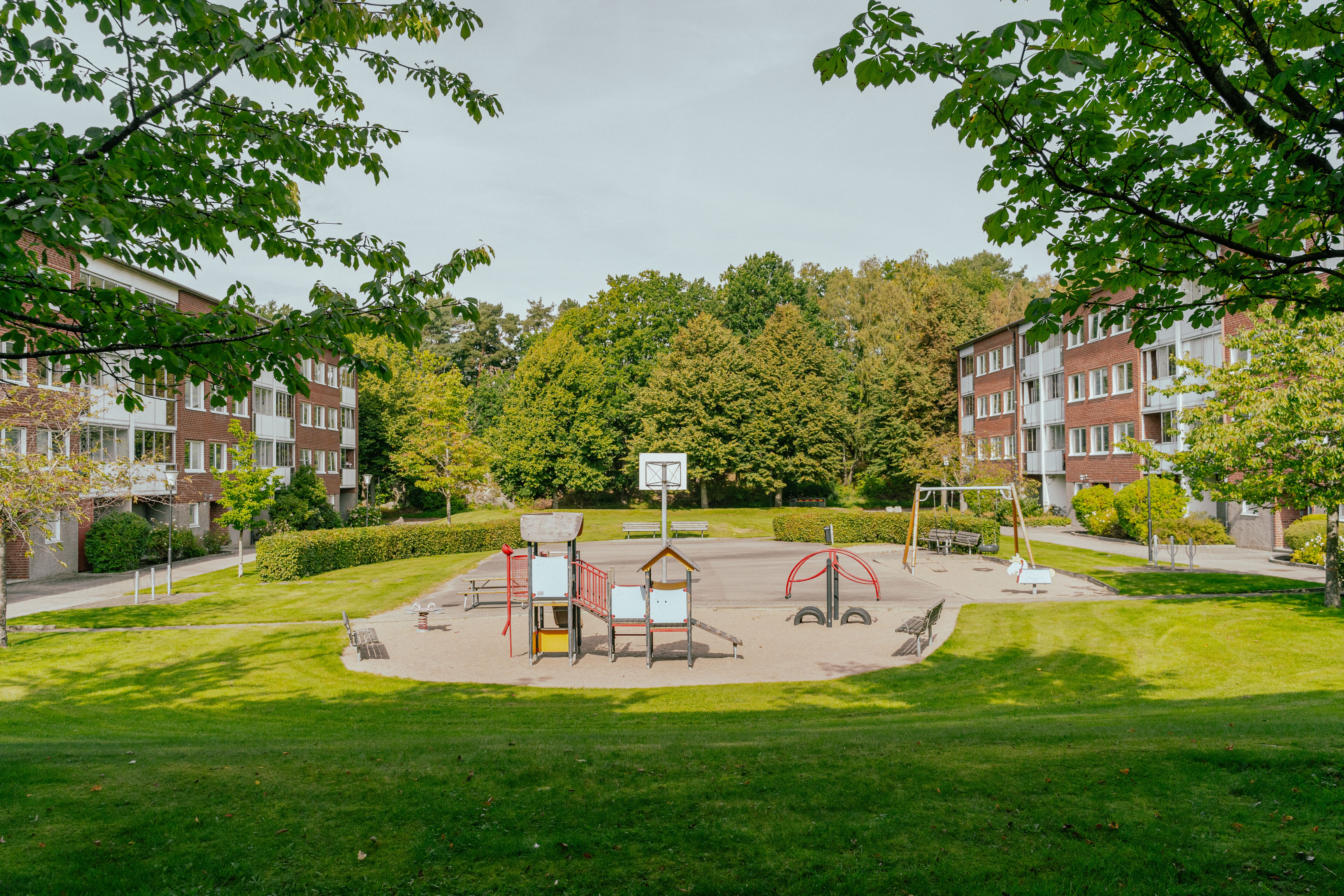 En lekplats omgiven av gräsmattor mellan två huslängor
