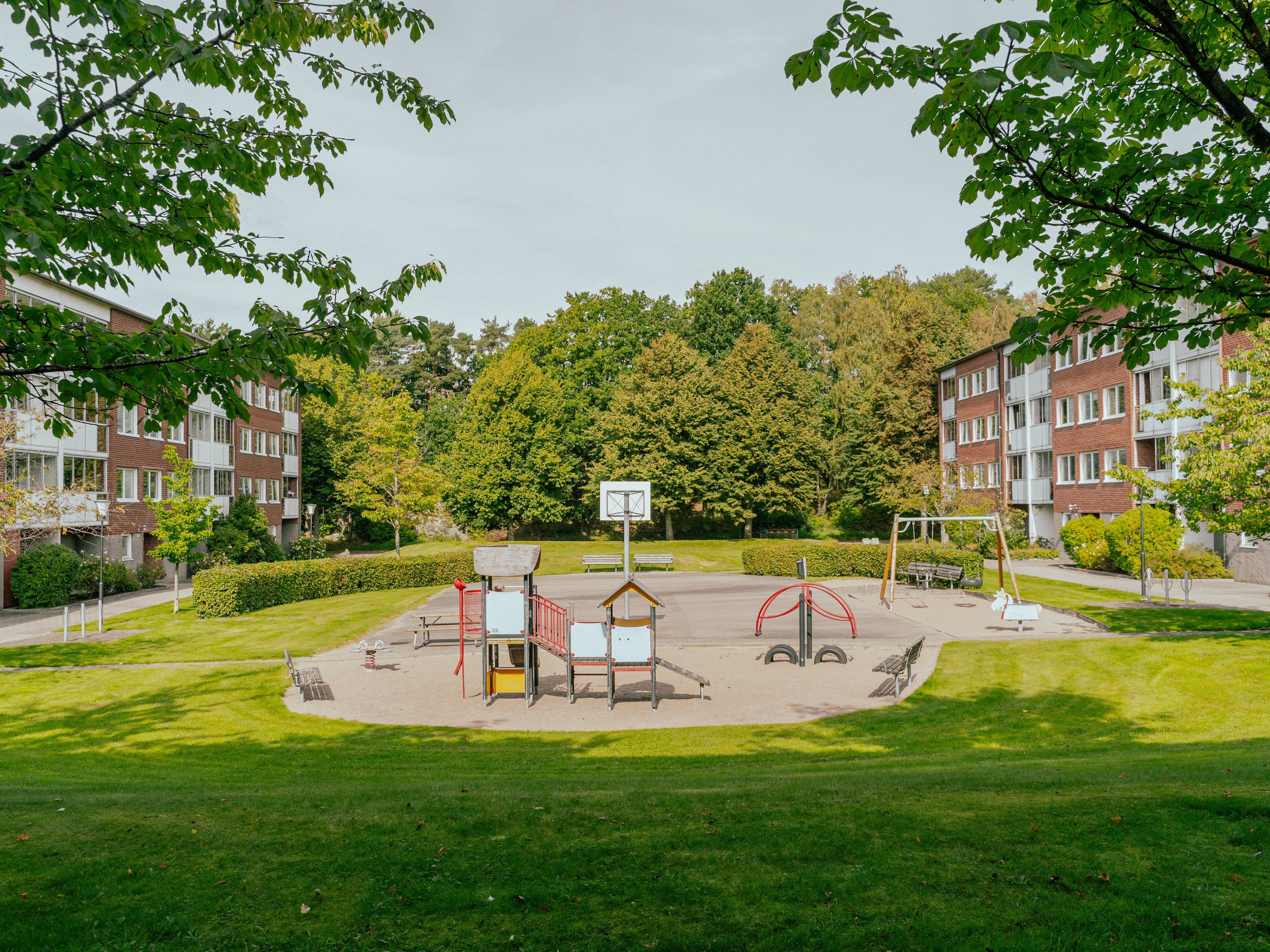 En lekplats omgiven av gräsmattor mellan två huslängor