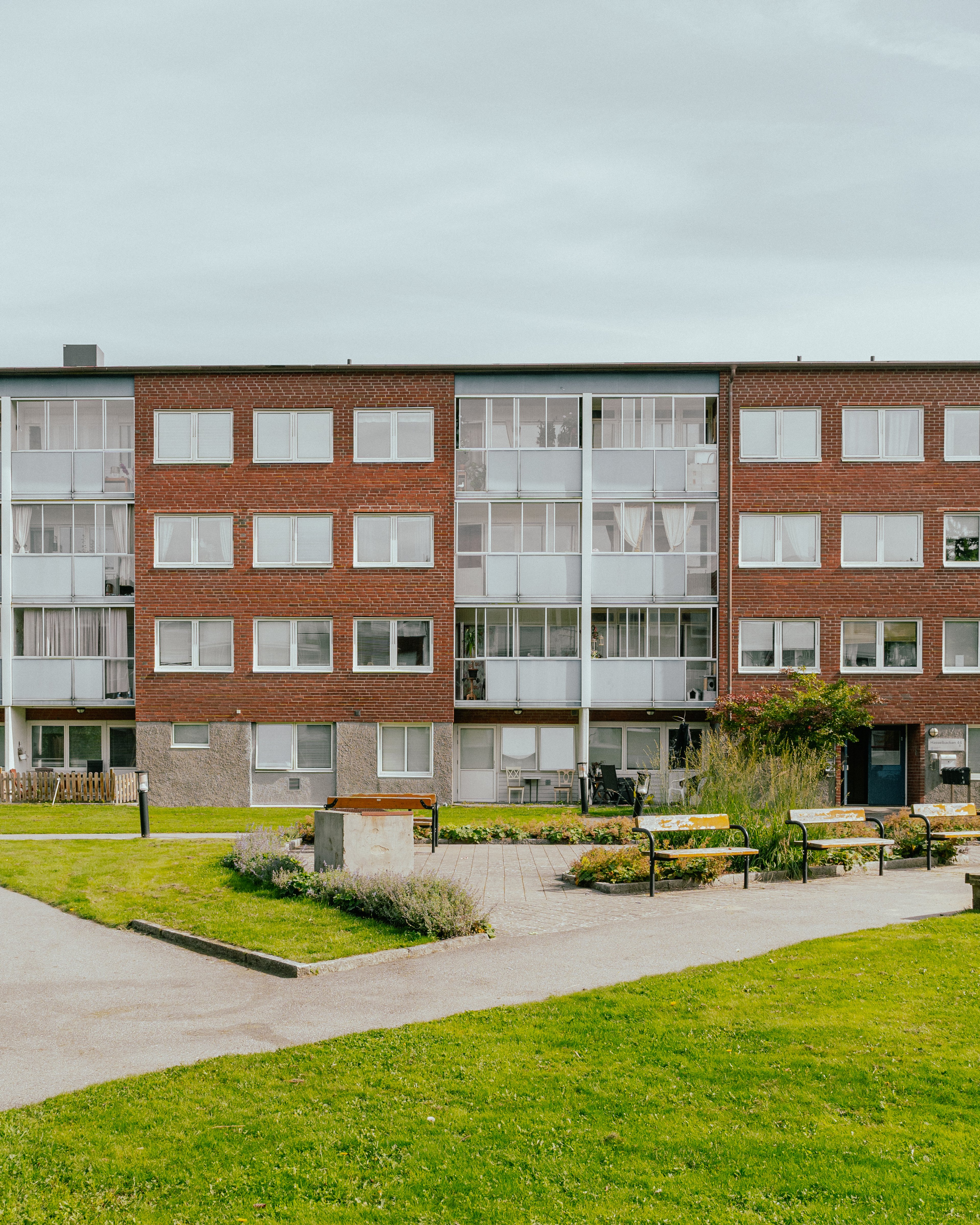 Stor gård med gräsmattor och parkbänkar framför ett lägenhetshus