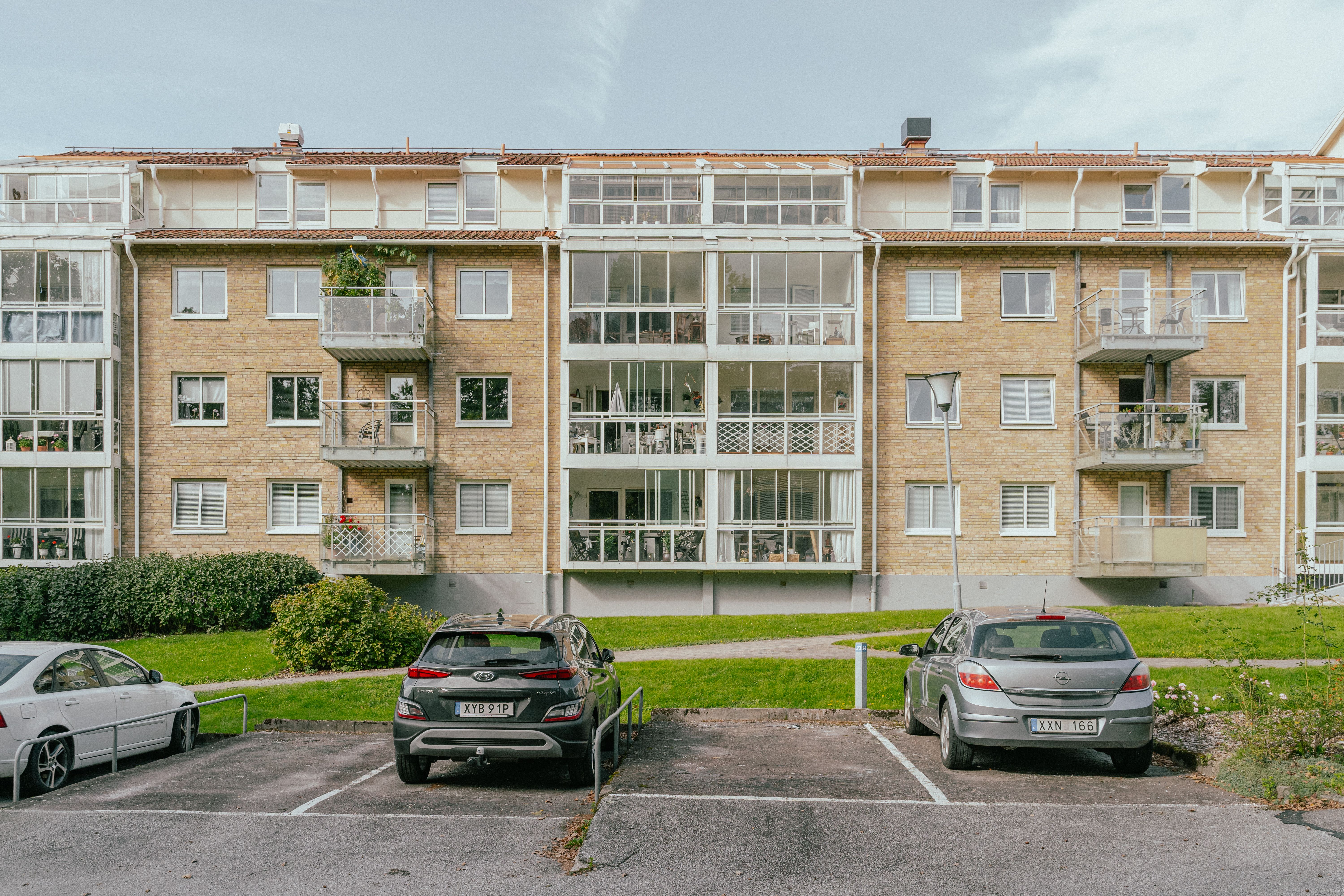 Parkeringsplatser med bilar framför ett hus och gräsmatta
