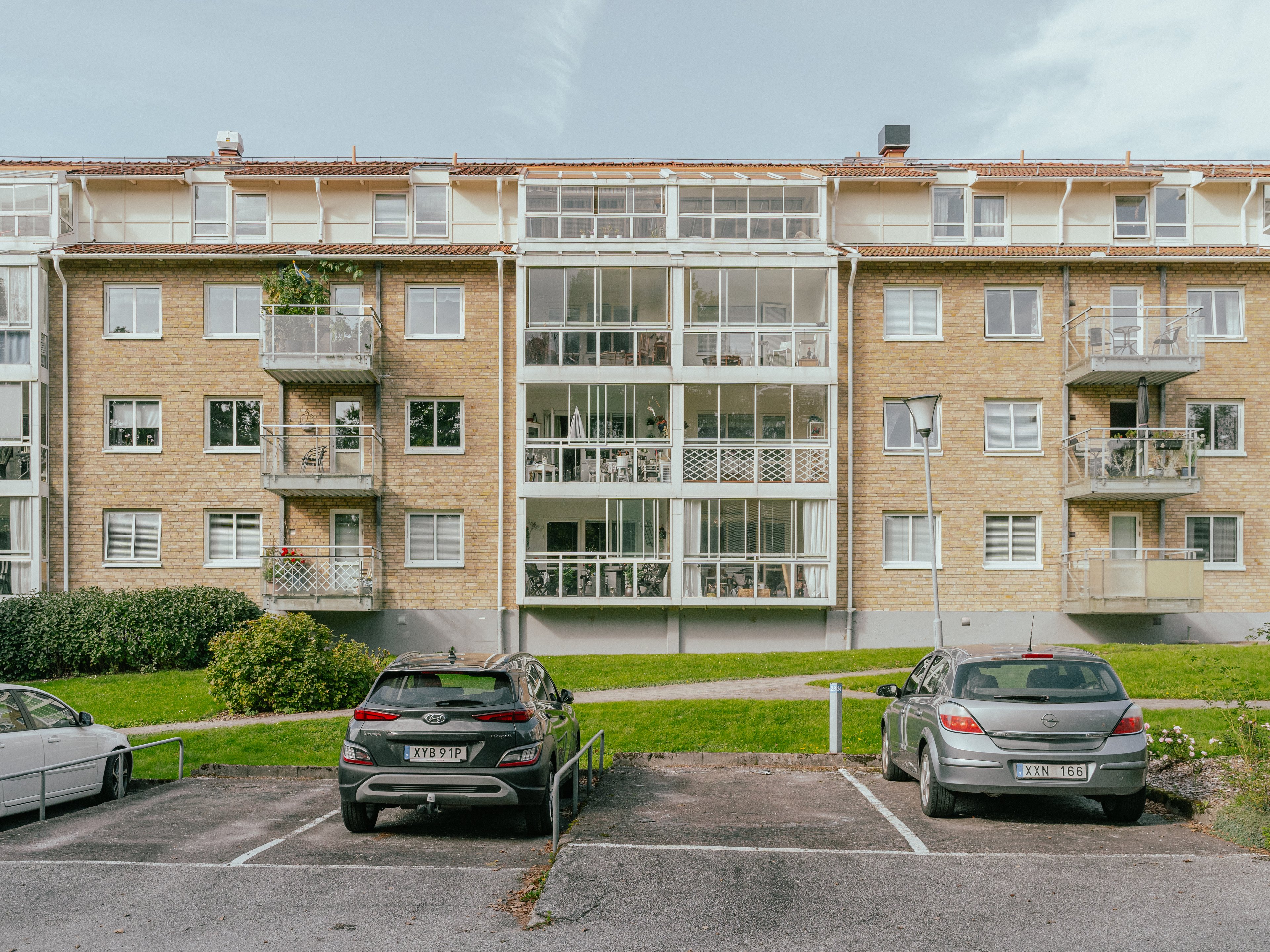 Parkeringsplatser med bilar framför ett hus och gräsmatta