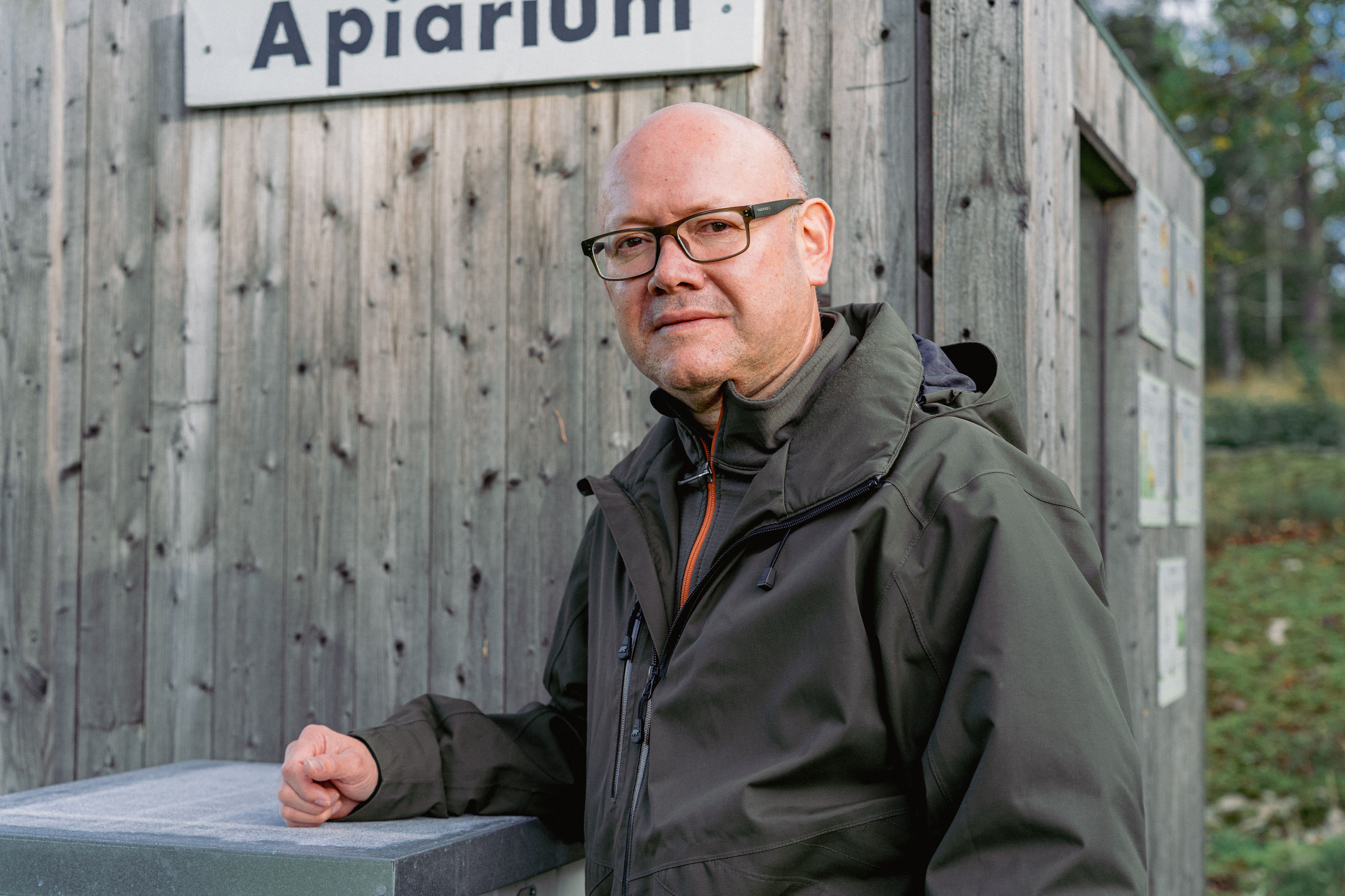 Porträtt på en man som står bredvid en bikupa