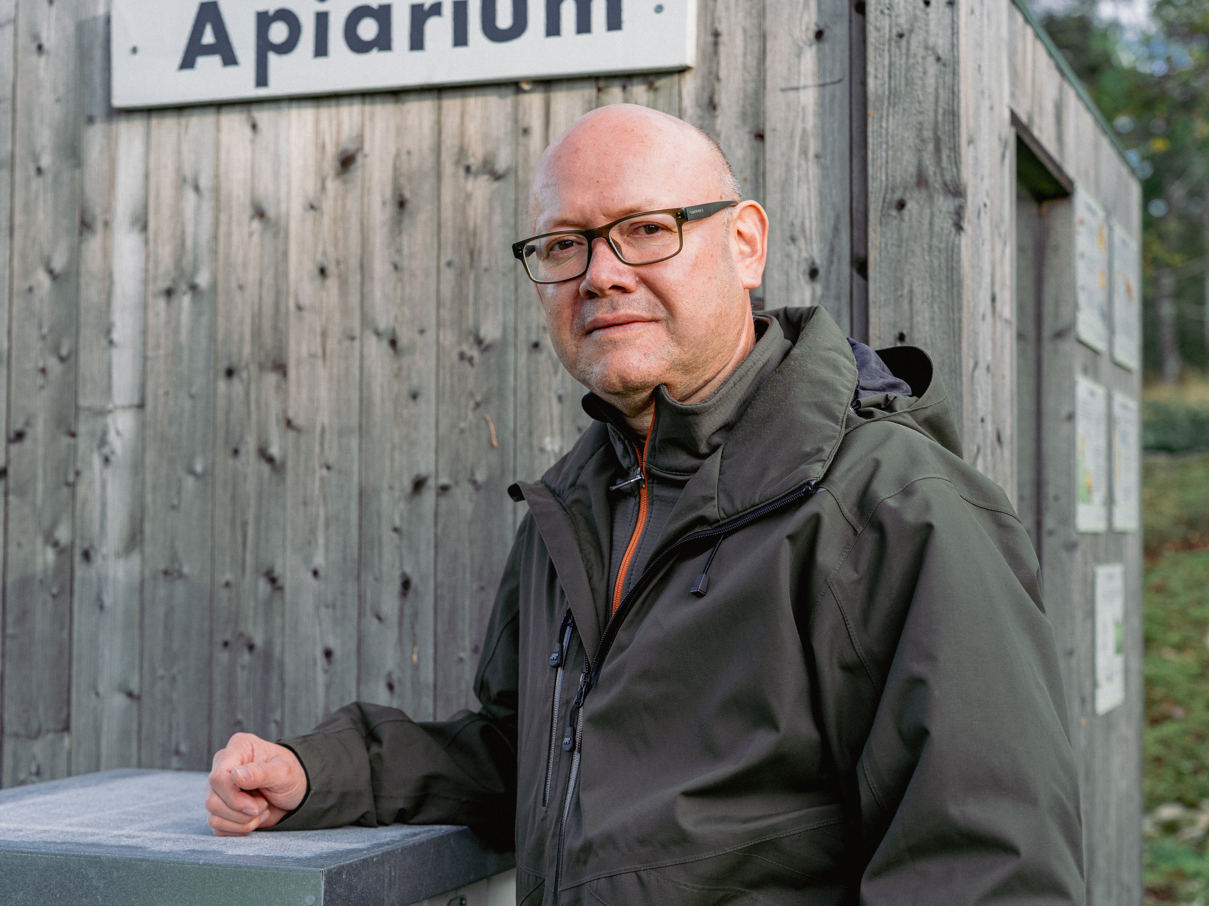 Porträtt på en man som står bredvid en bikupa