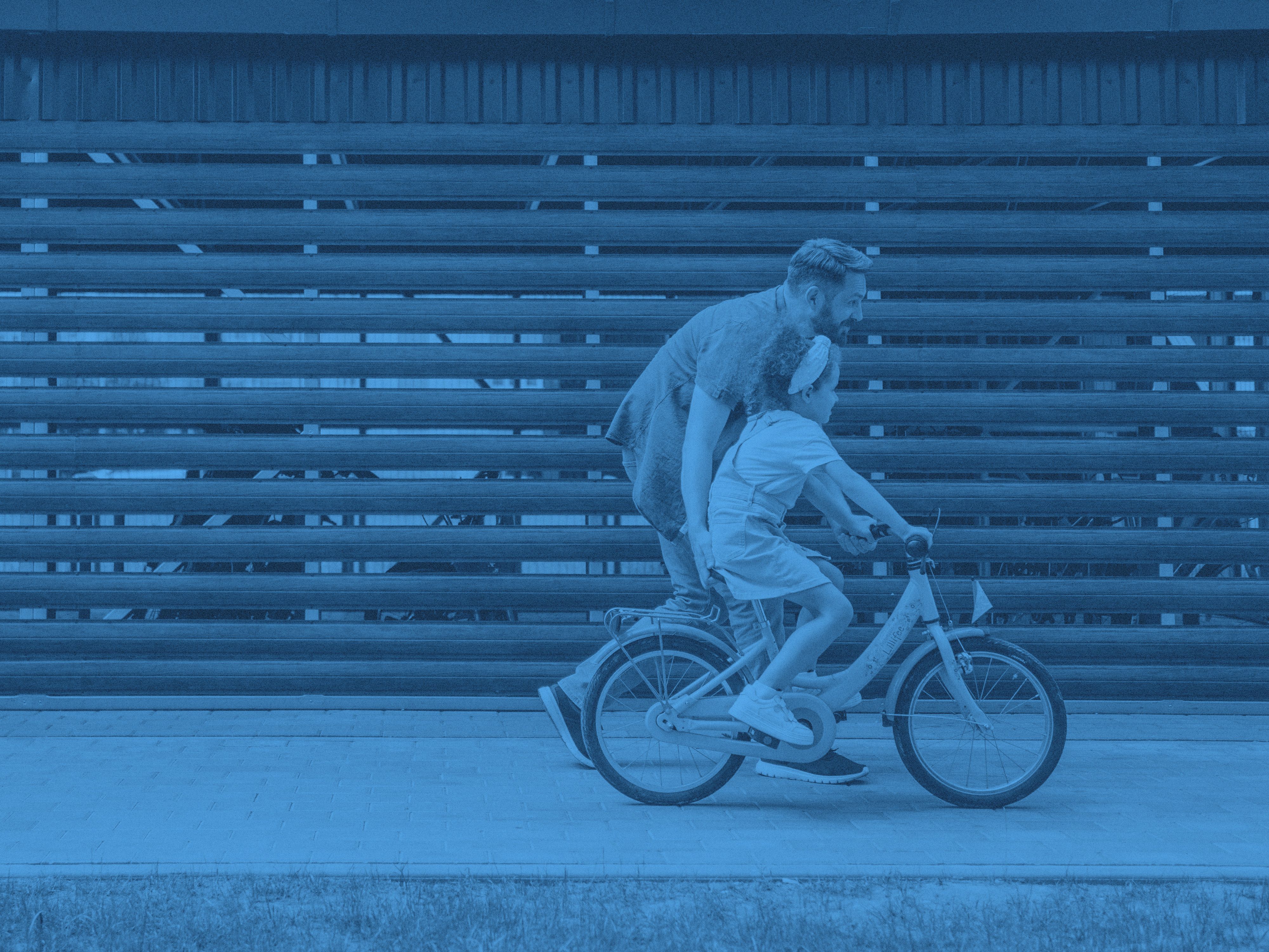 En man hjälper en yngre flicka att cykla