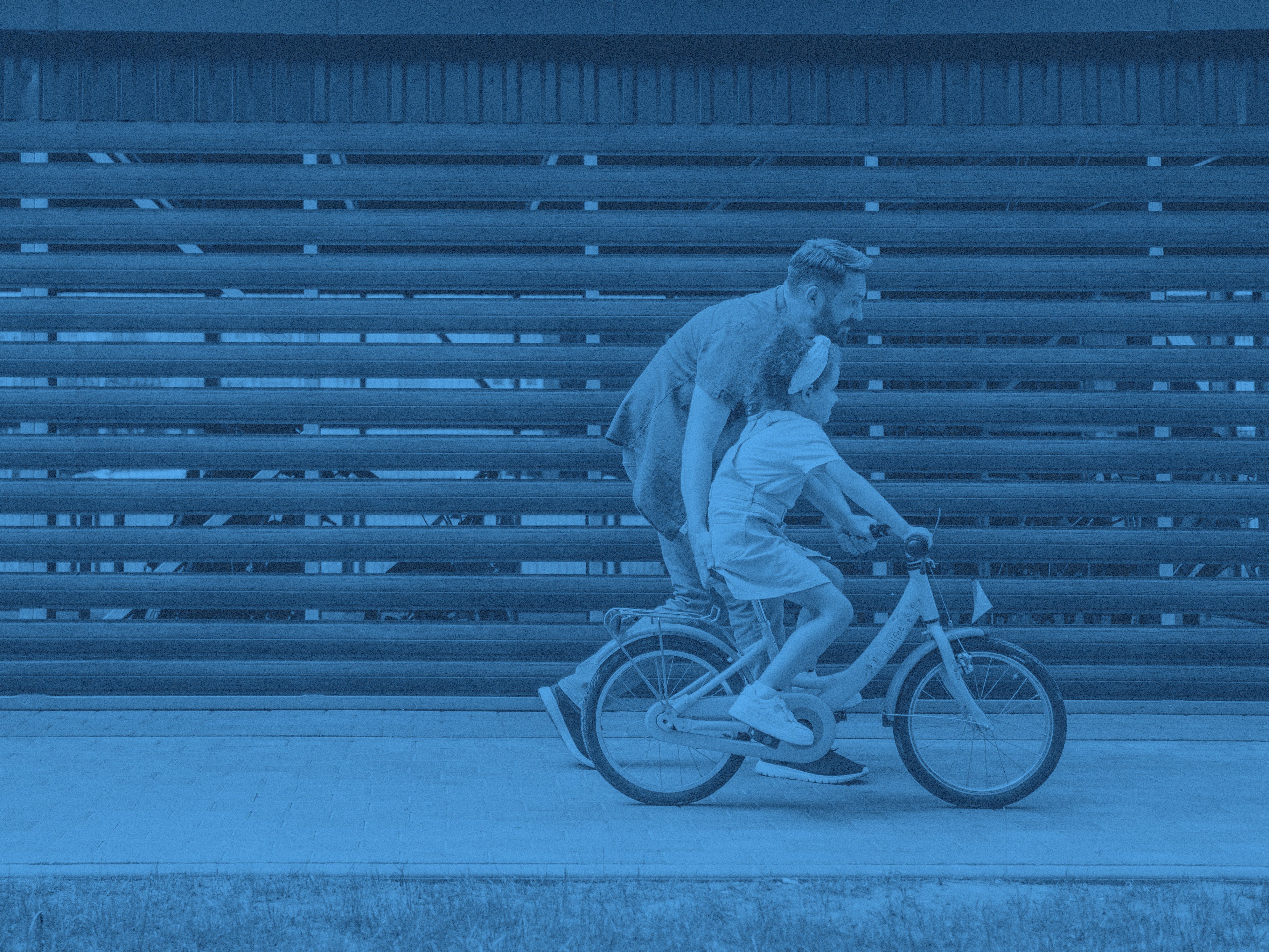 En man hjälper en yngre flicka att cykla