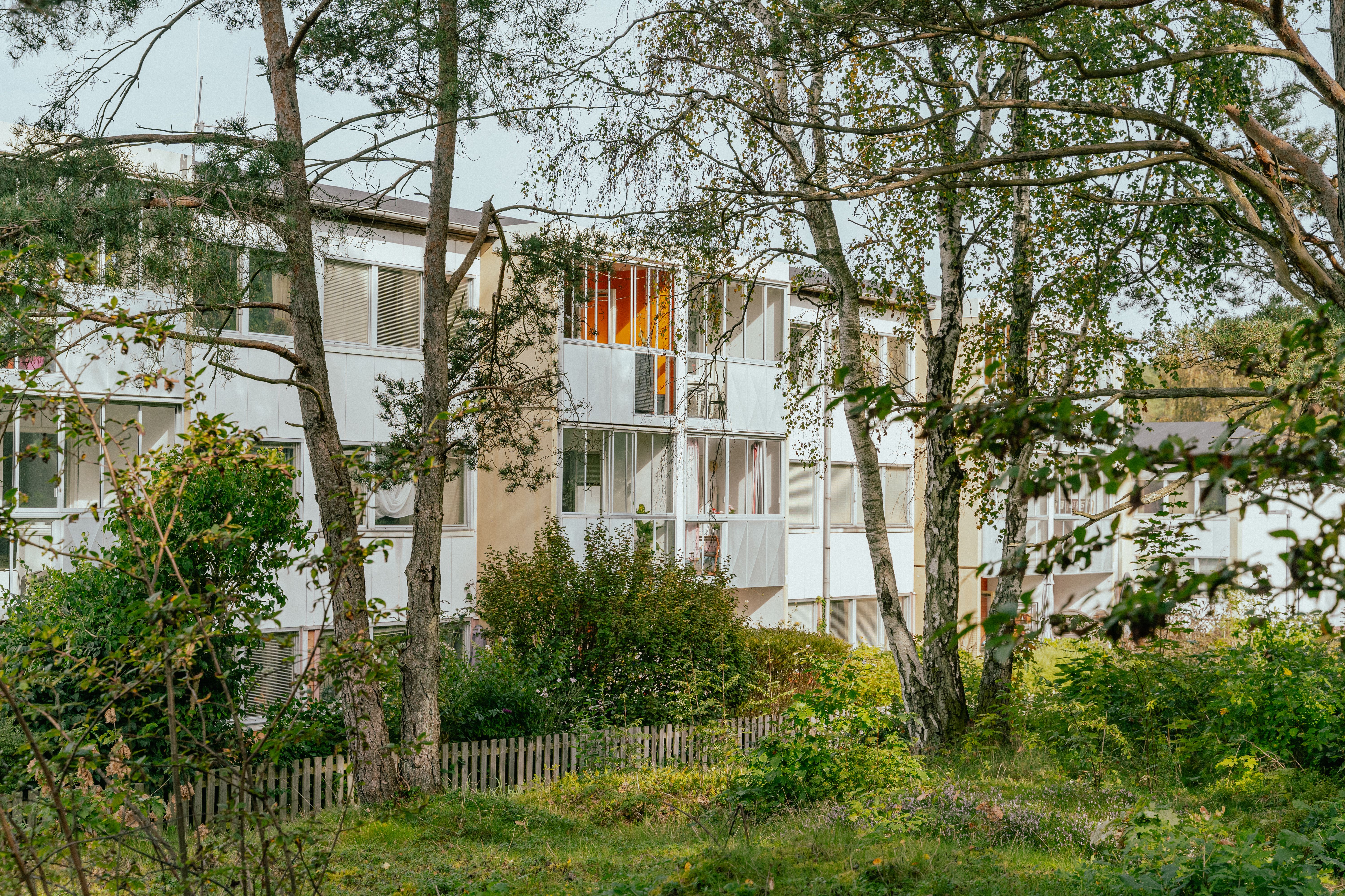 Ett hus med balkonger och uteplatser sett genom en skog