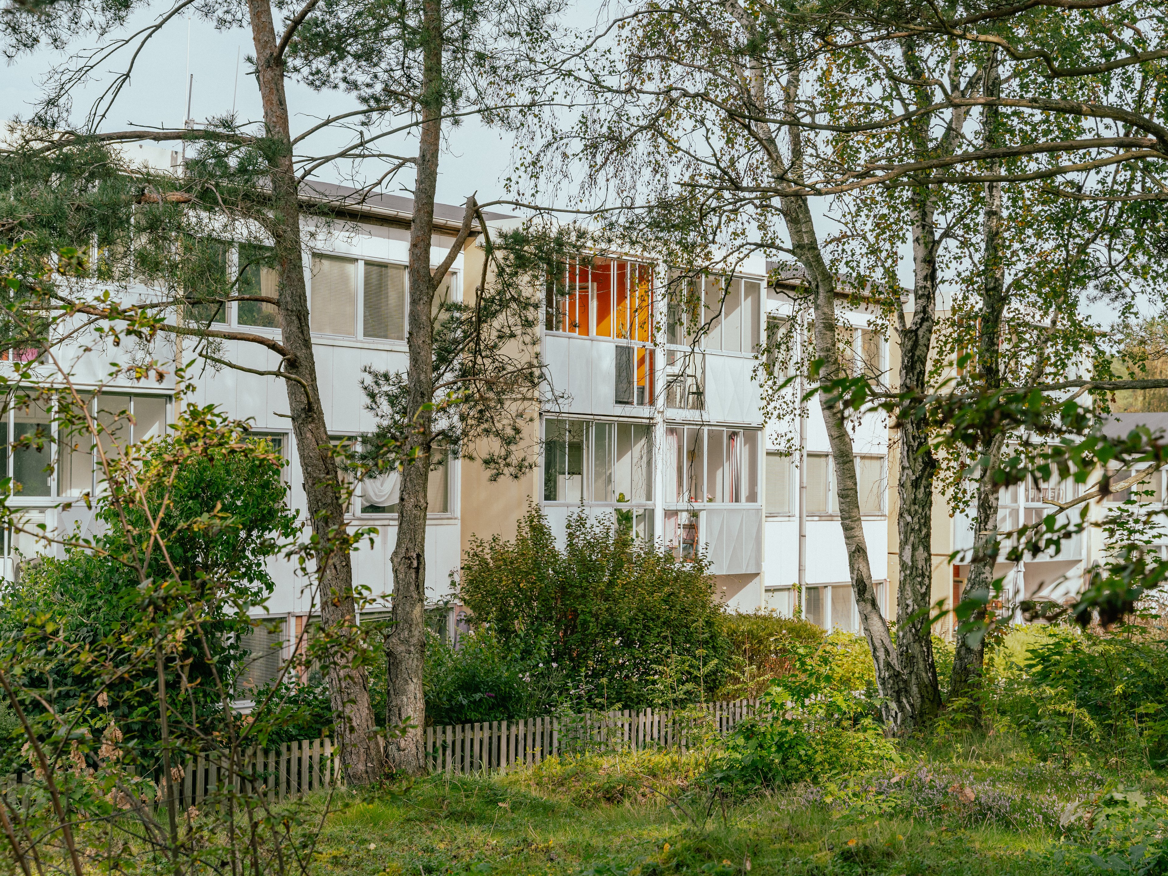 Ett hus med balkonger och uteplatser sett genom en skog