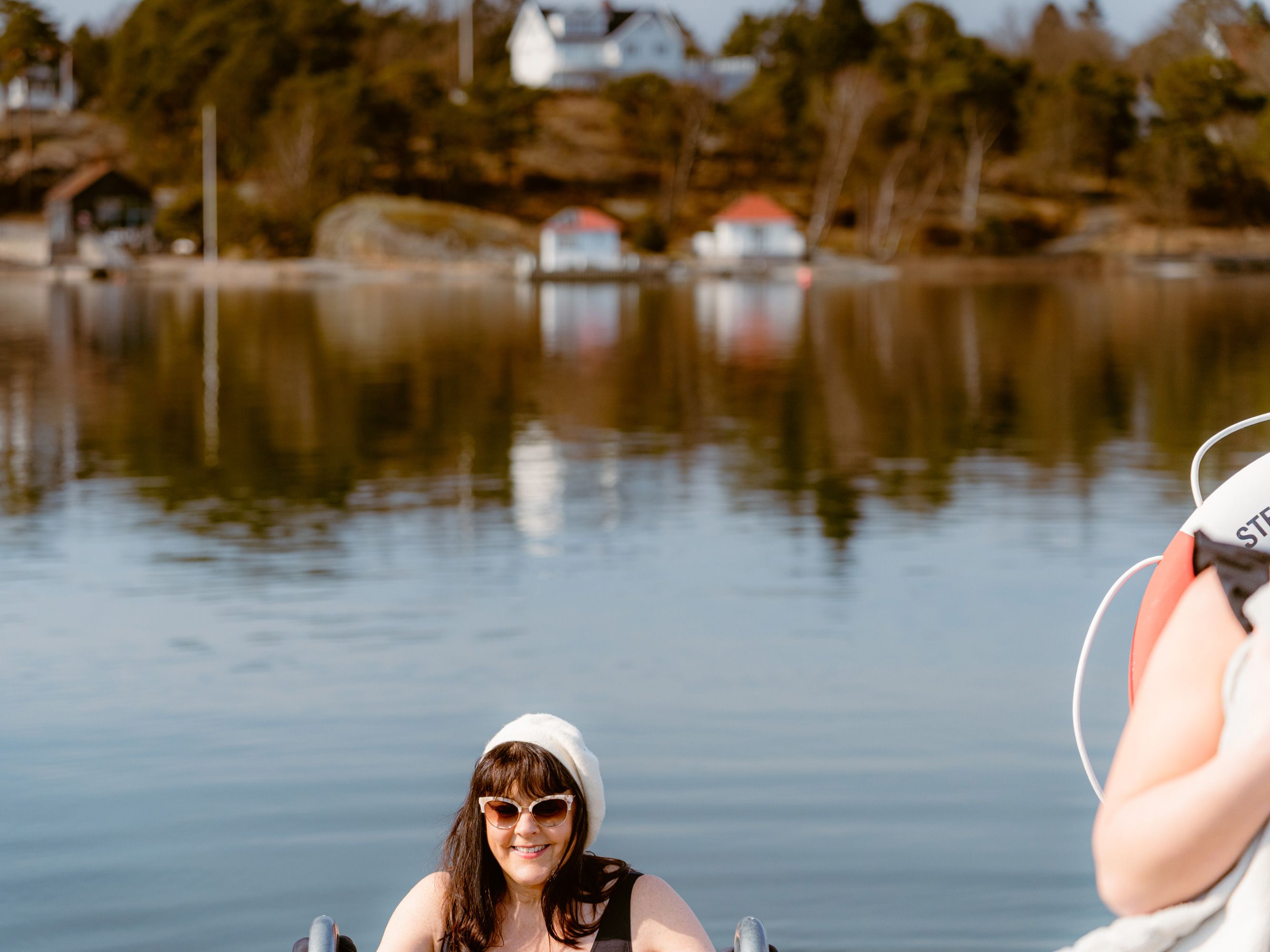 En kvinna på en badstege på väg ner i vattnet