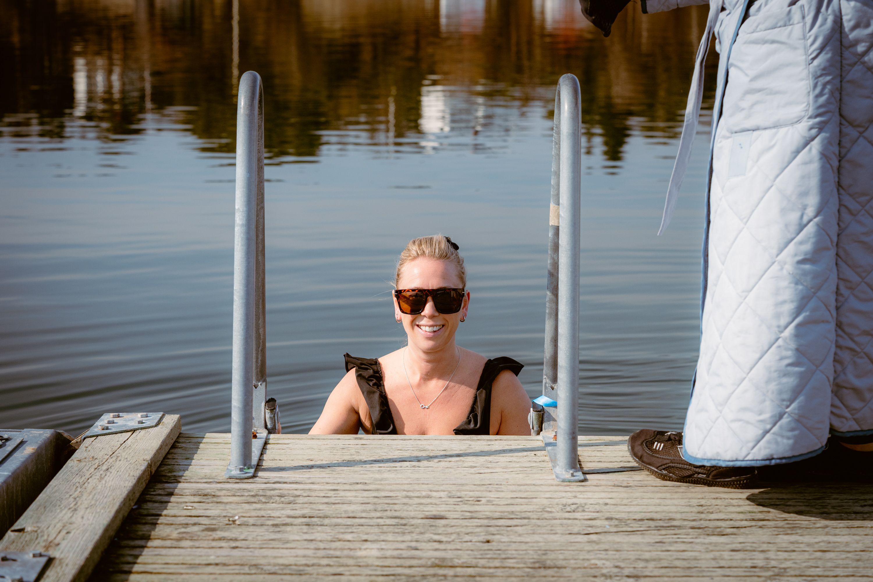 En kvinna på en badstege på väg ner i vattnet