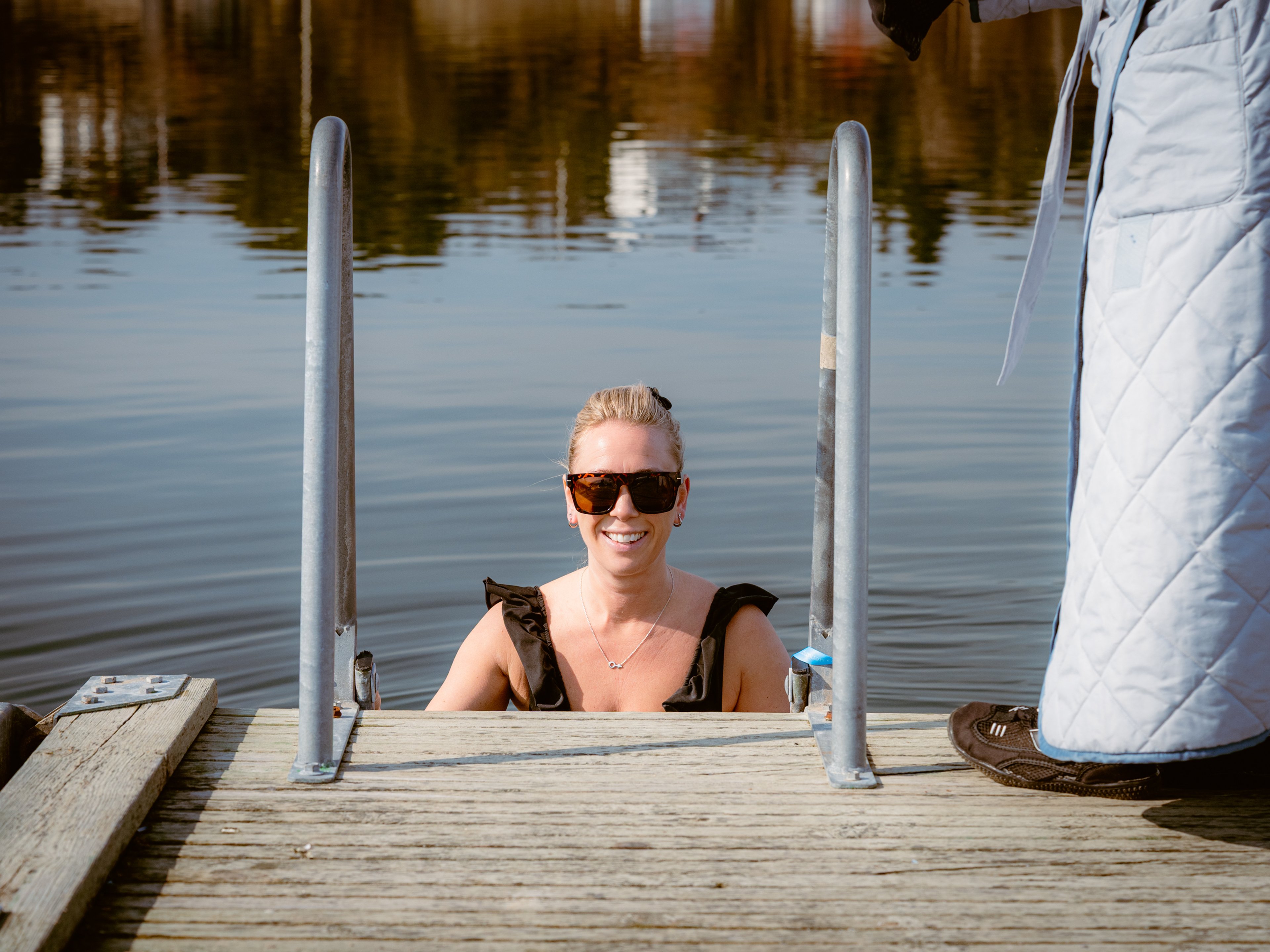 En kvinna på en badstege på väg ner i vattnet