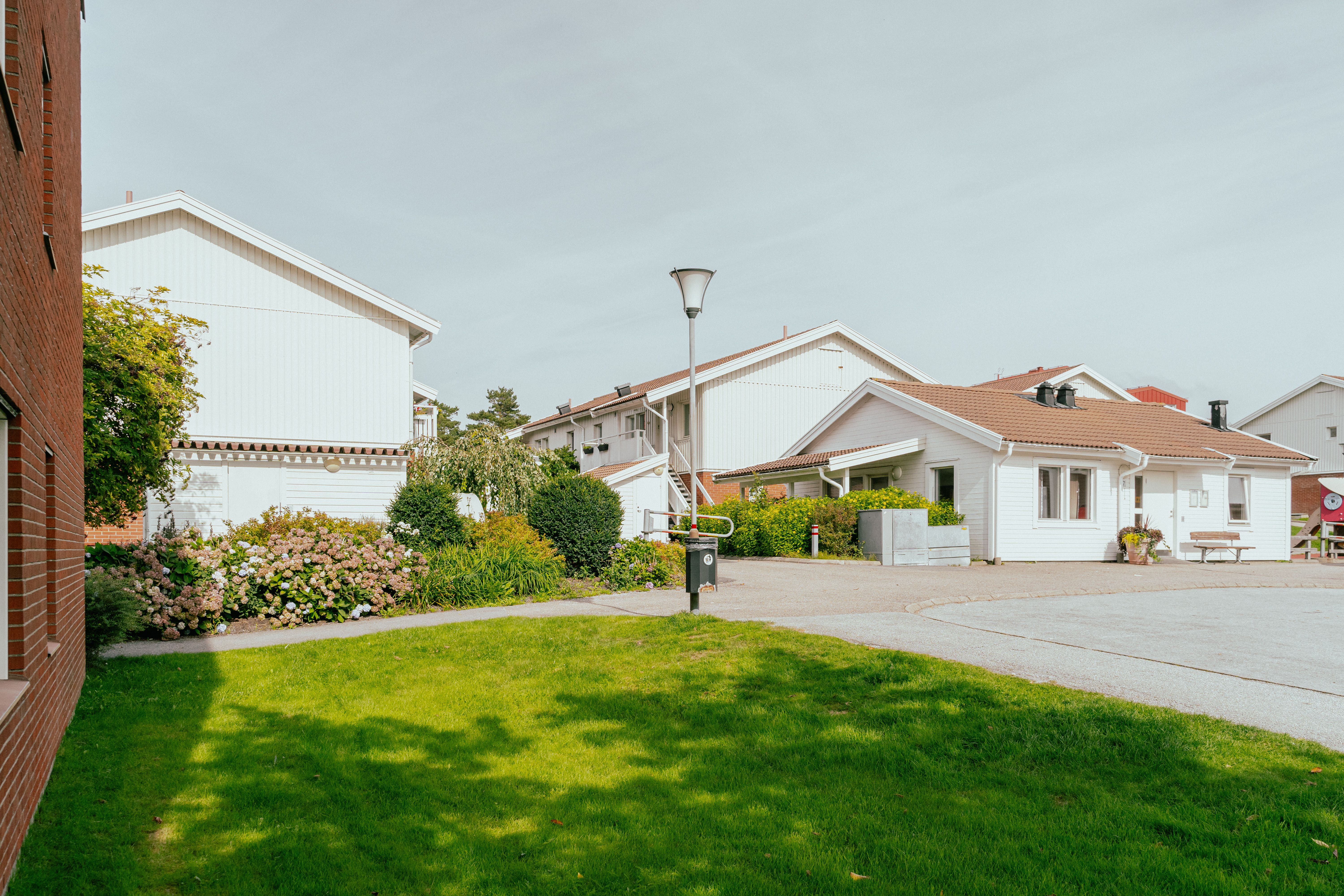 En gräsmatta framför en tegelfasad och tvåvåningshus i bakgrunden