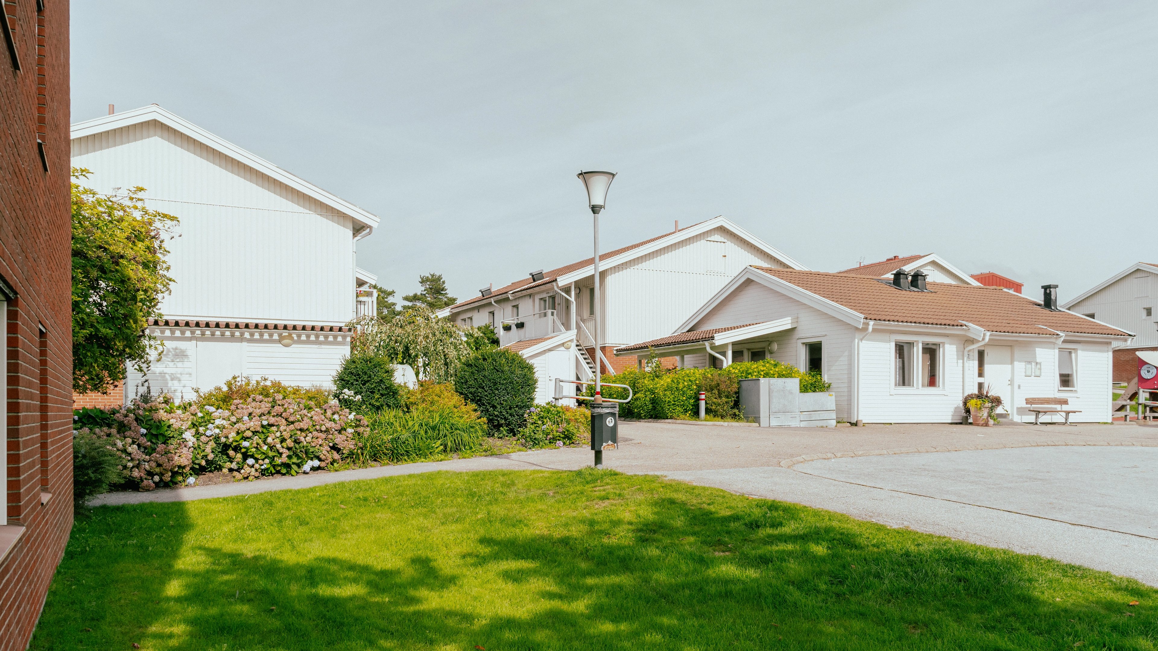 En gräsmatta framför en tegelfasad och tvåvåningshus i bakgrunden