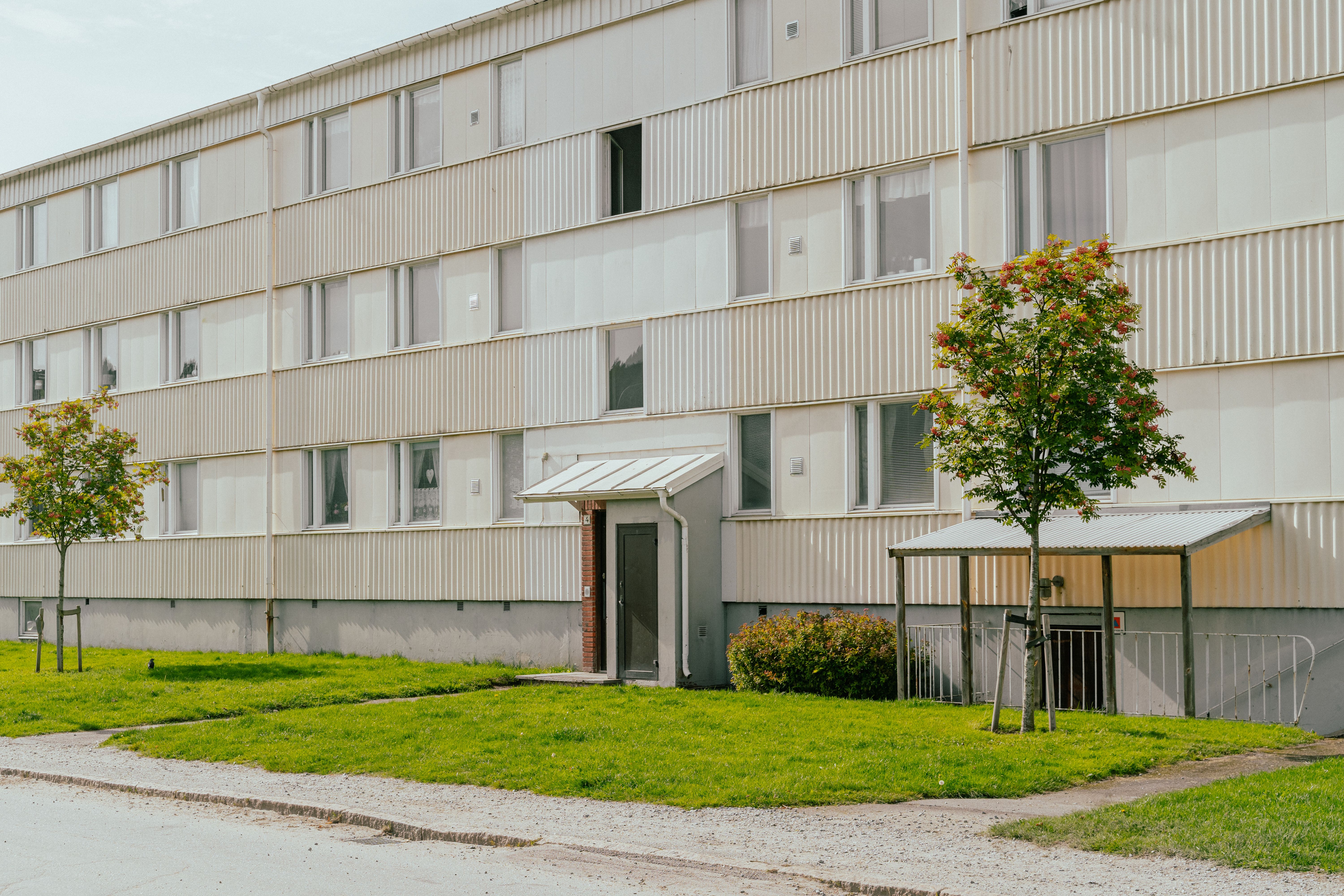 Fasaden av ett trevåningshus med träd framför