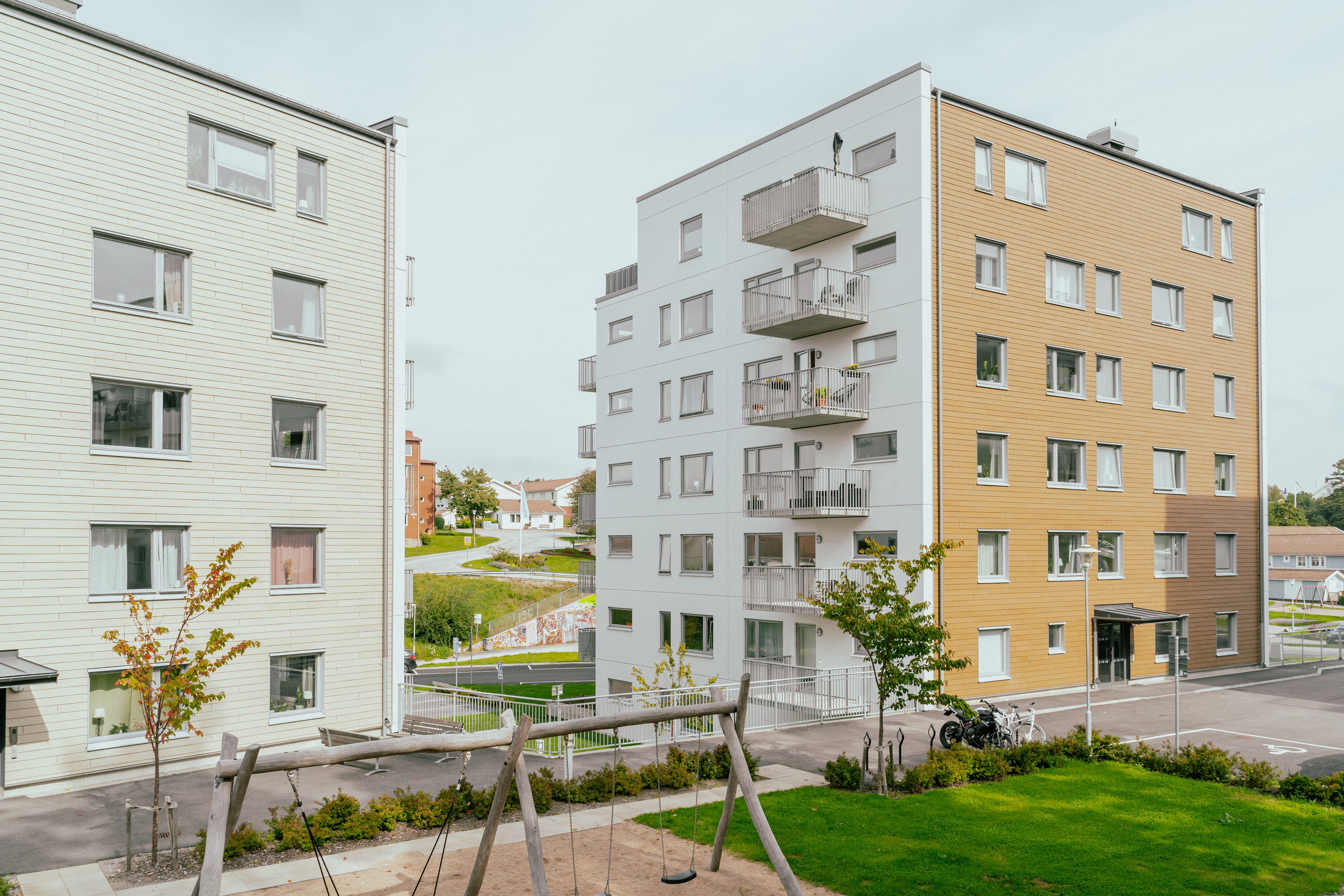 En innergård mellan två sexvåningshus, en lekplats med gungor i mitten