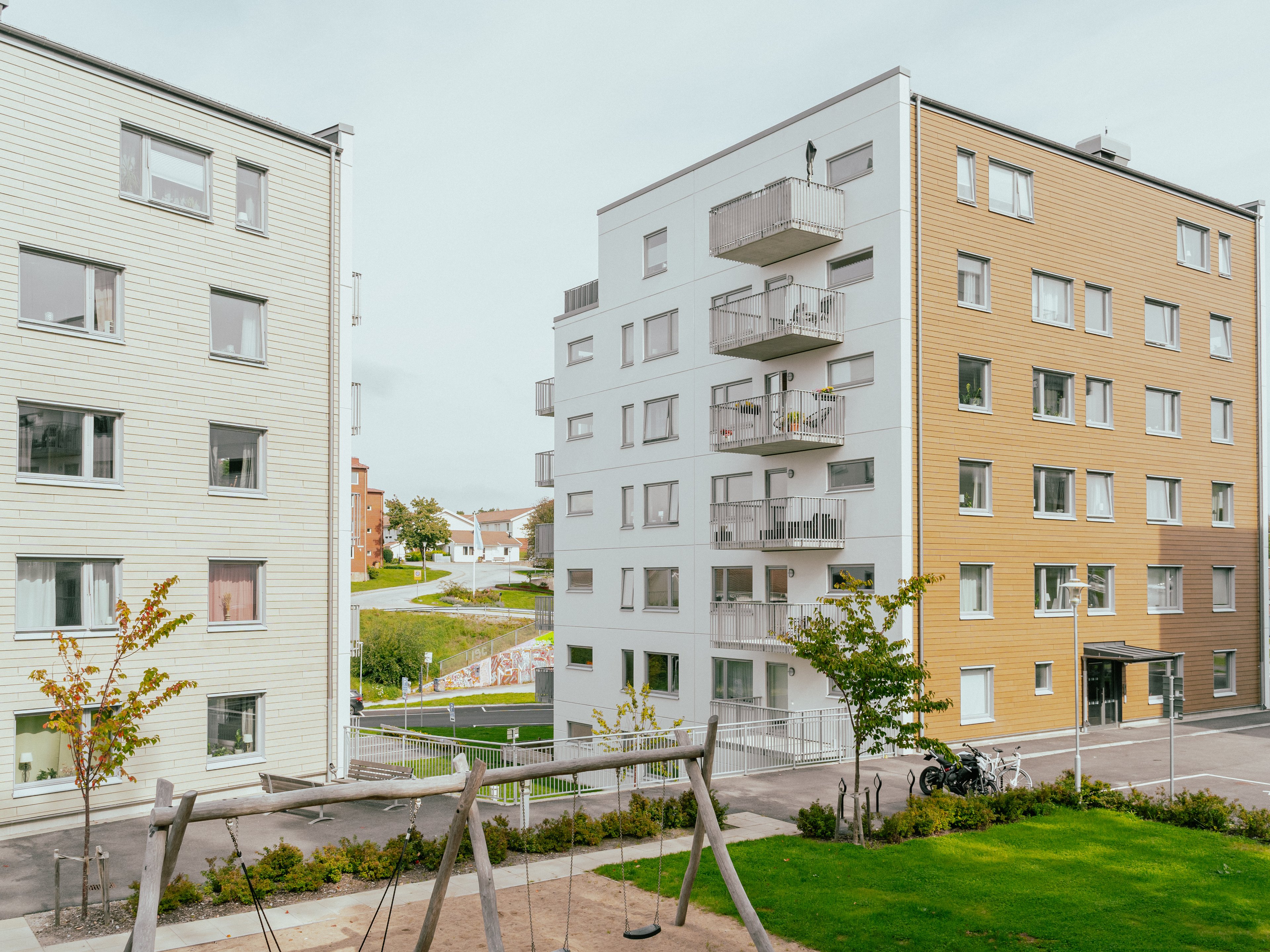 En innergård mellan två sexvåningshus, en lekplats med gungor i mitten