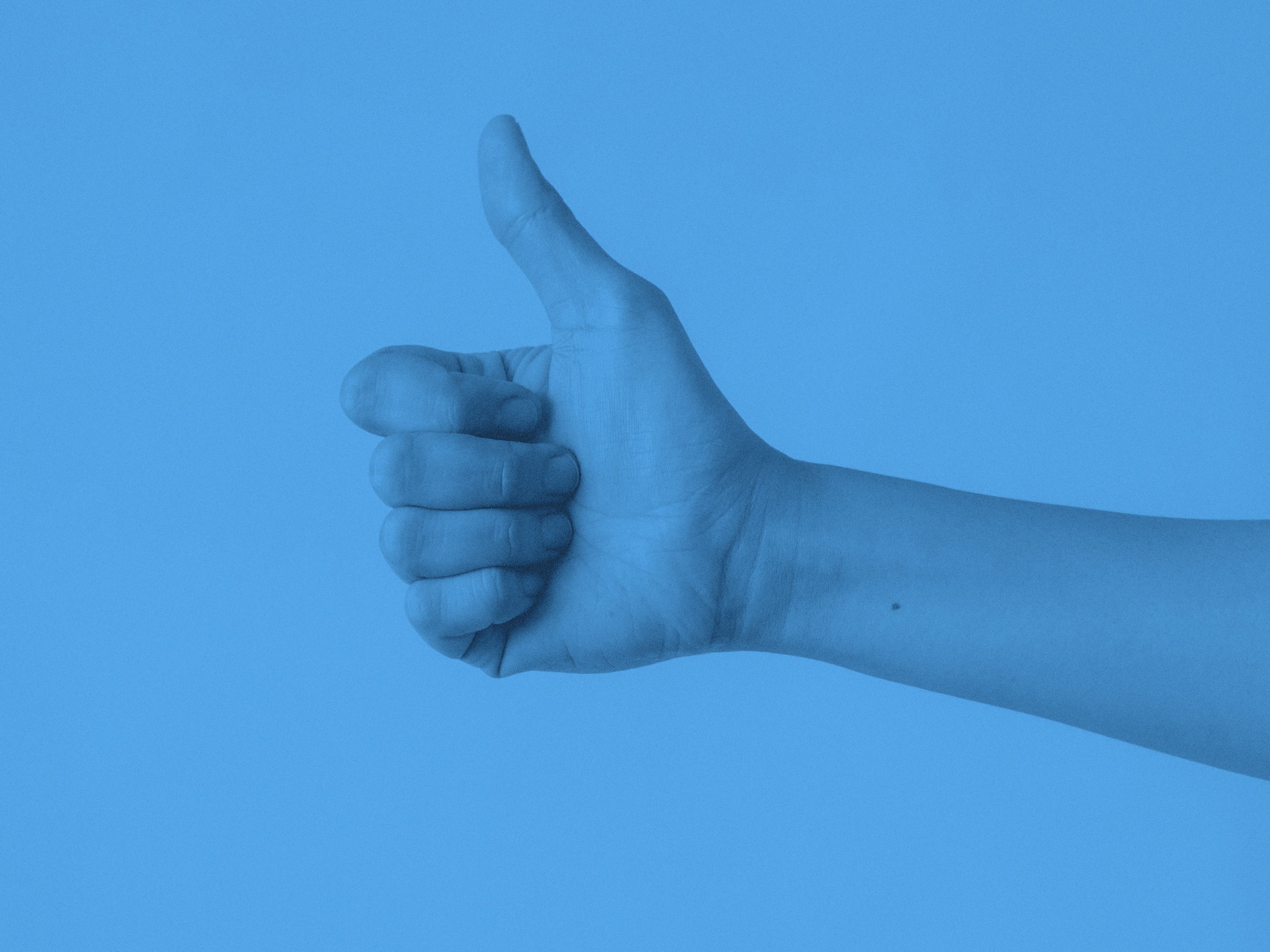 En hand som gör tecknet tumme upp