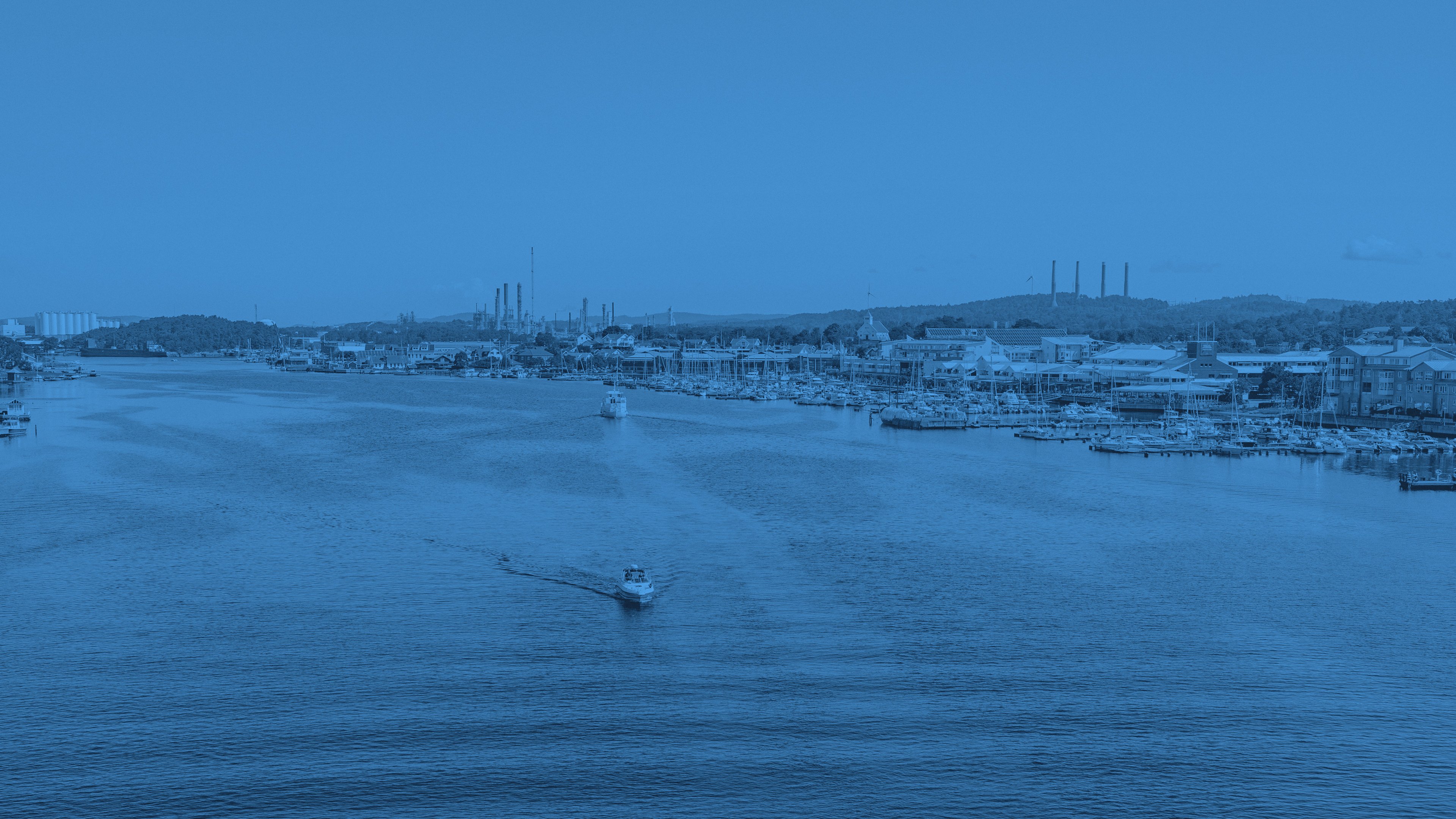 Utsikt över Stenungsunds småbåtshamn och en båt som färdas på vattnet