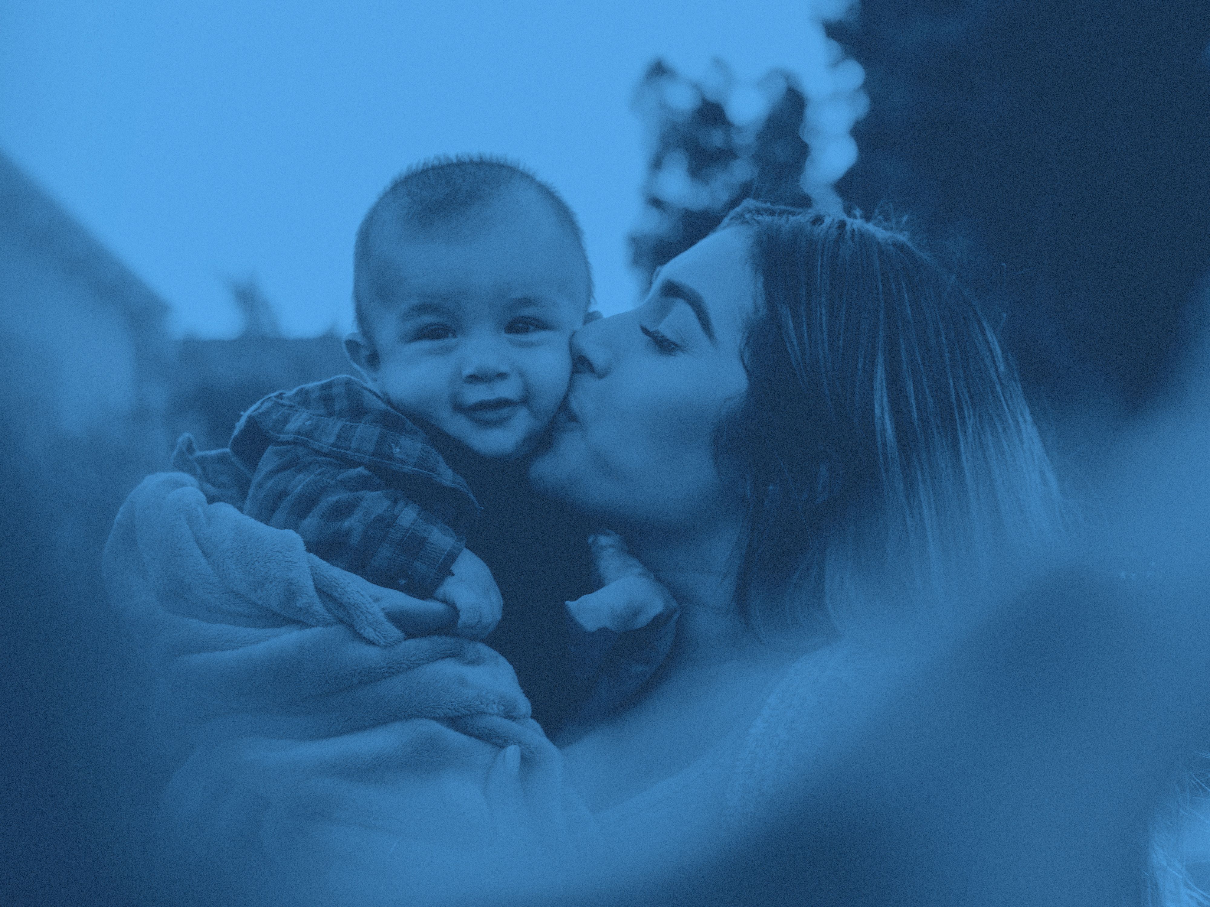 En mamma pussar litet barn på kinden