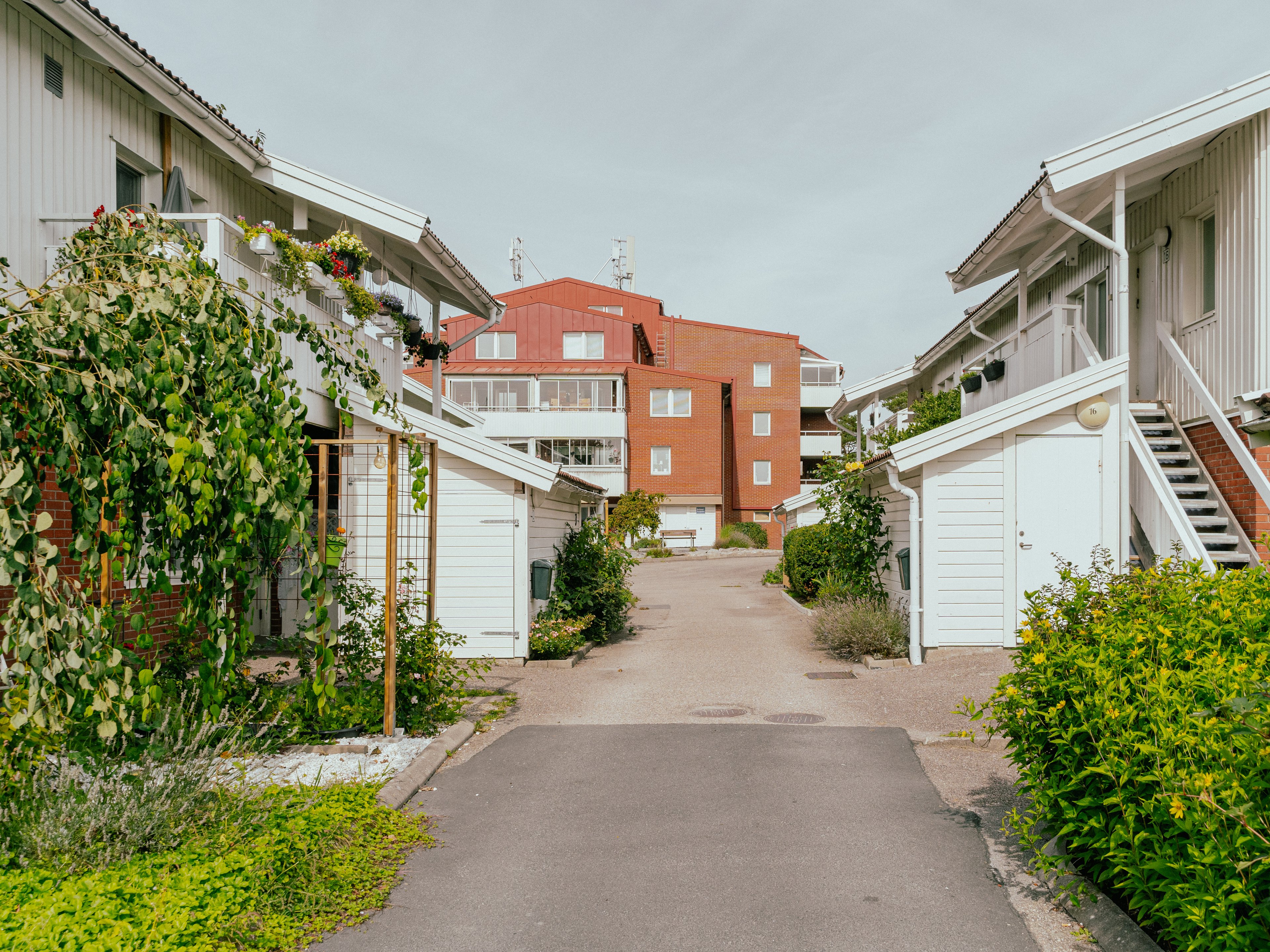 En liten gata med radhus på bägge sidor och ett flervåningshus i bakgrunden