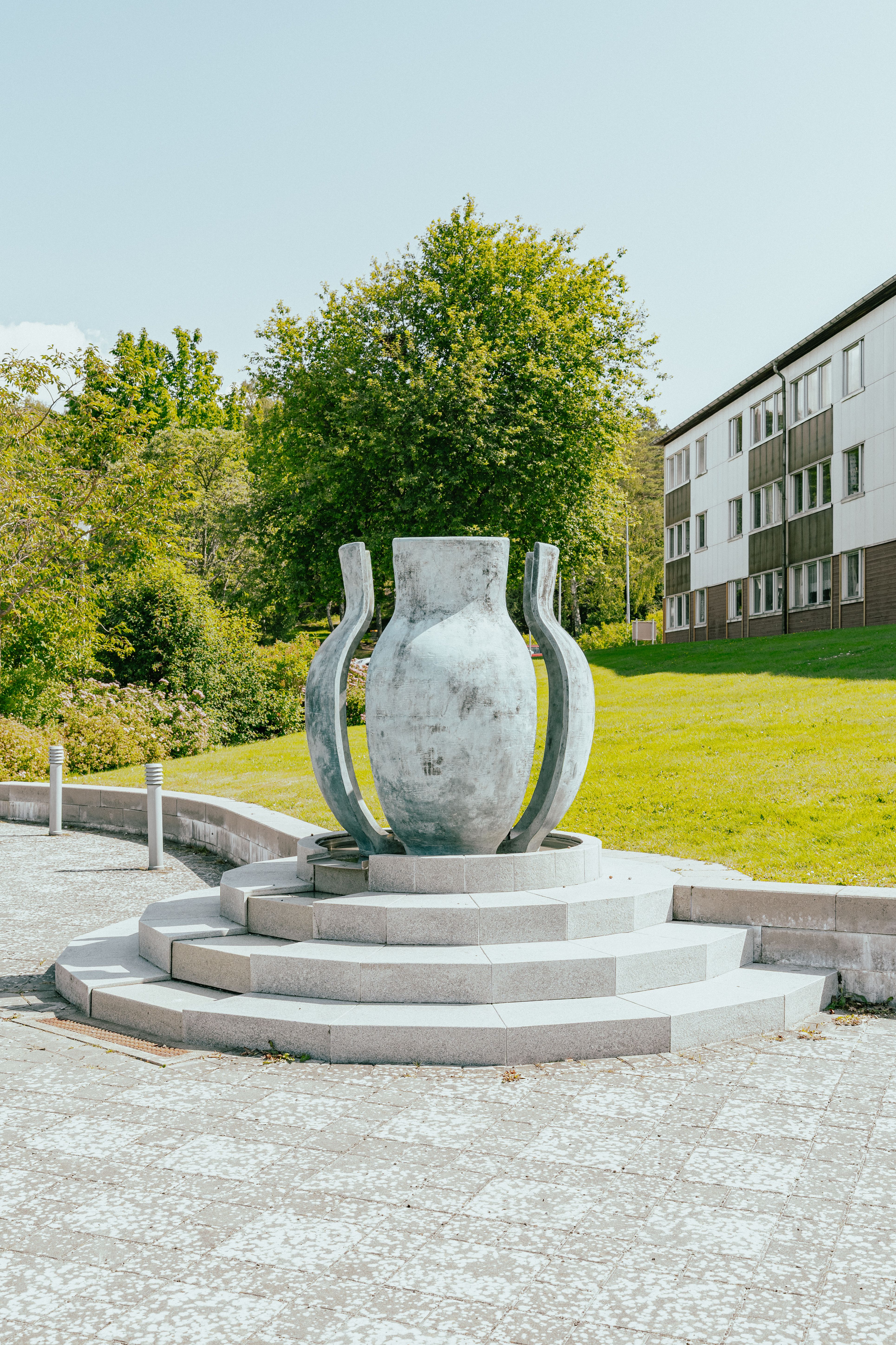 Ett konstverk som består av ett stort kärl, i delar, som står på en upphöjd granit-trappa
