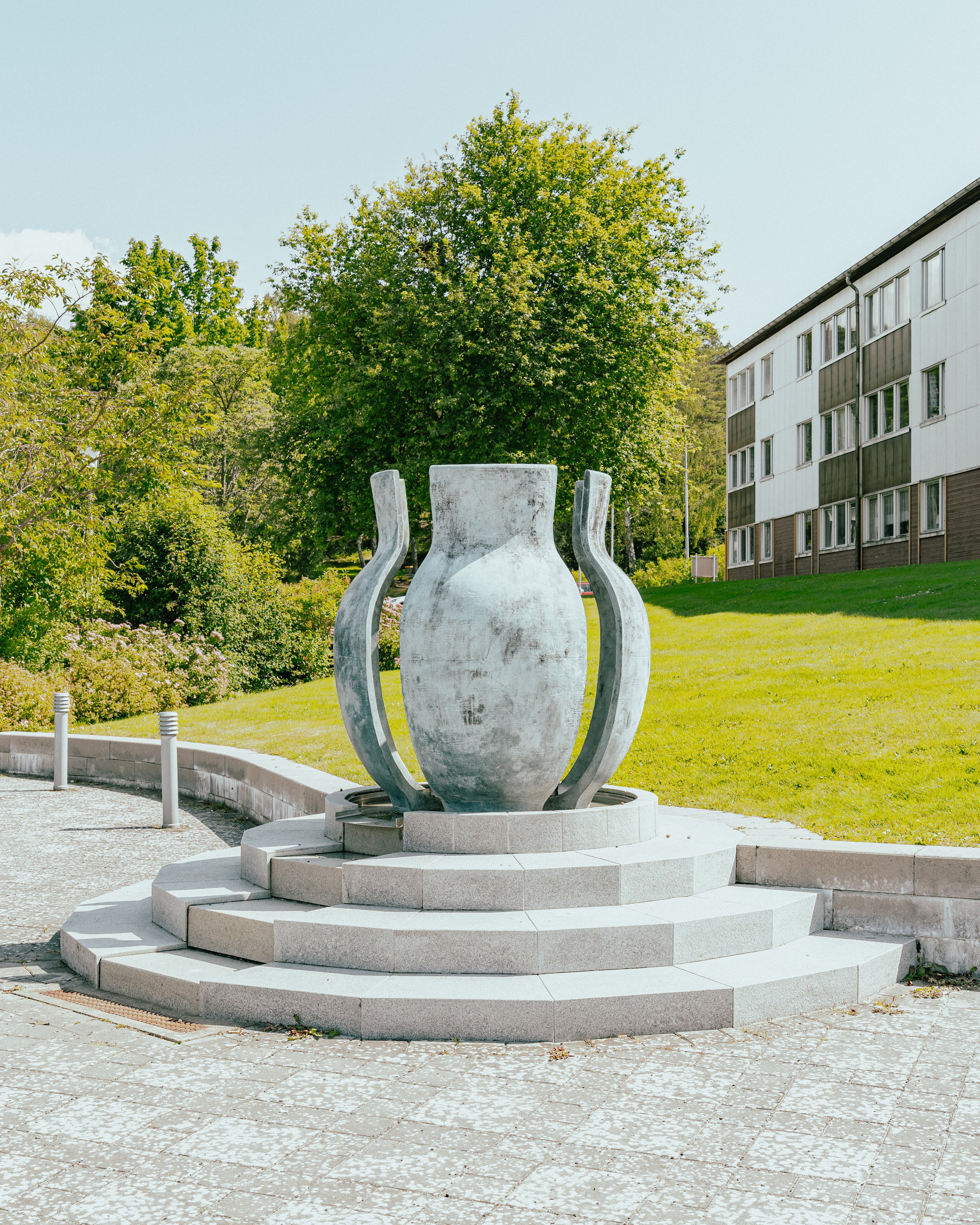 Ett konstverk som består av ett stort kärl, i delar, som står på en upphöjd granit-trappa