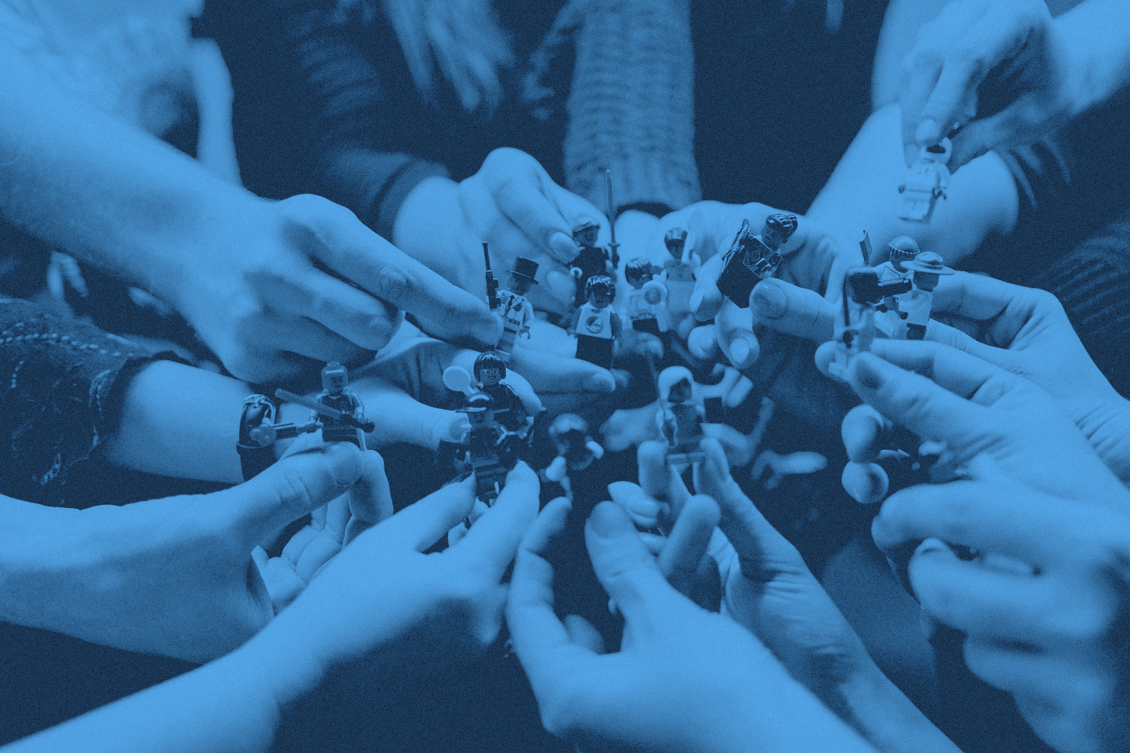 Massa händer som håller olika legofigurer