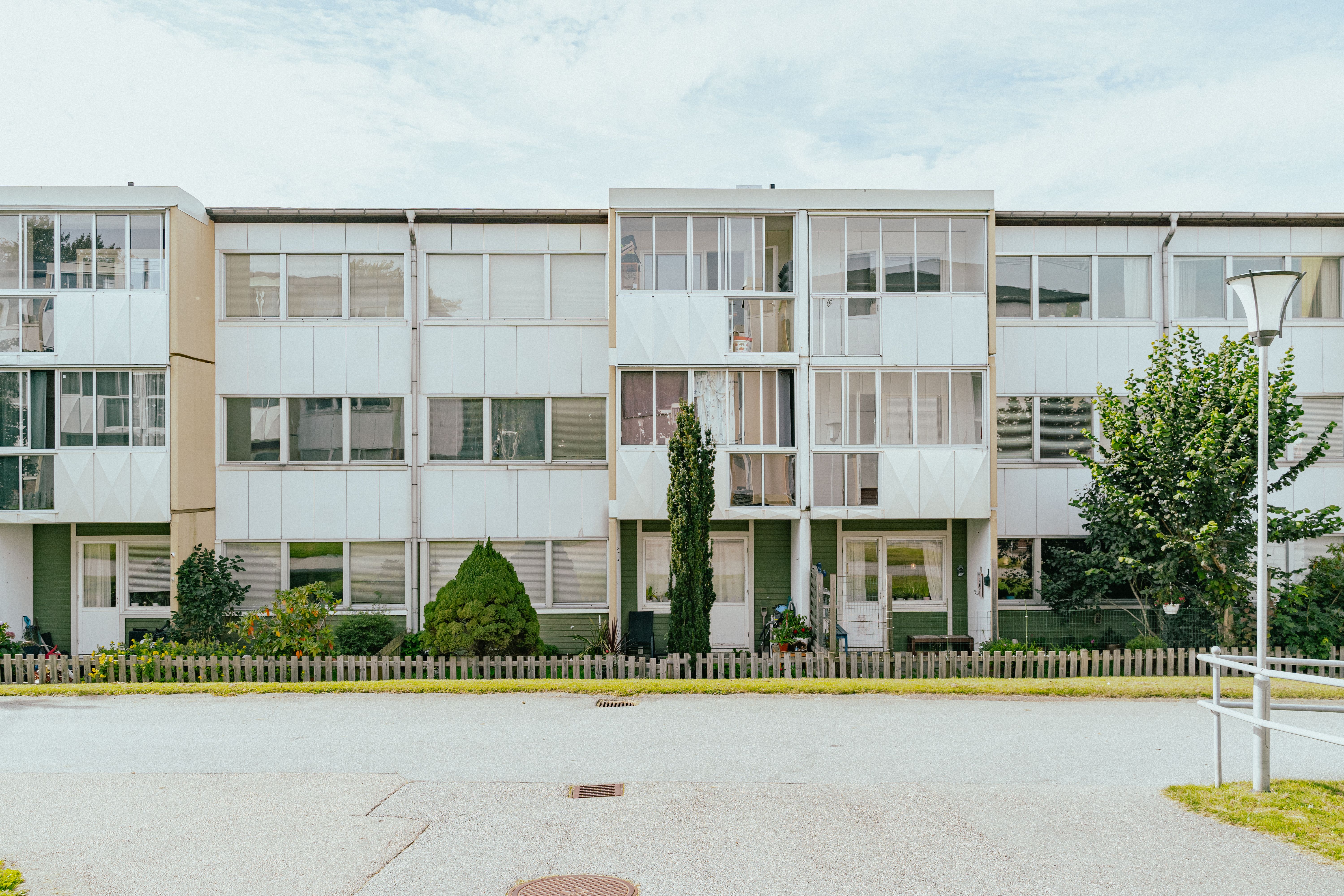 En hyres-länga med uteplatser och en asfalts-yta framför