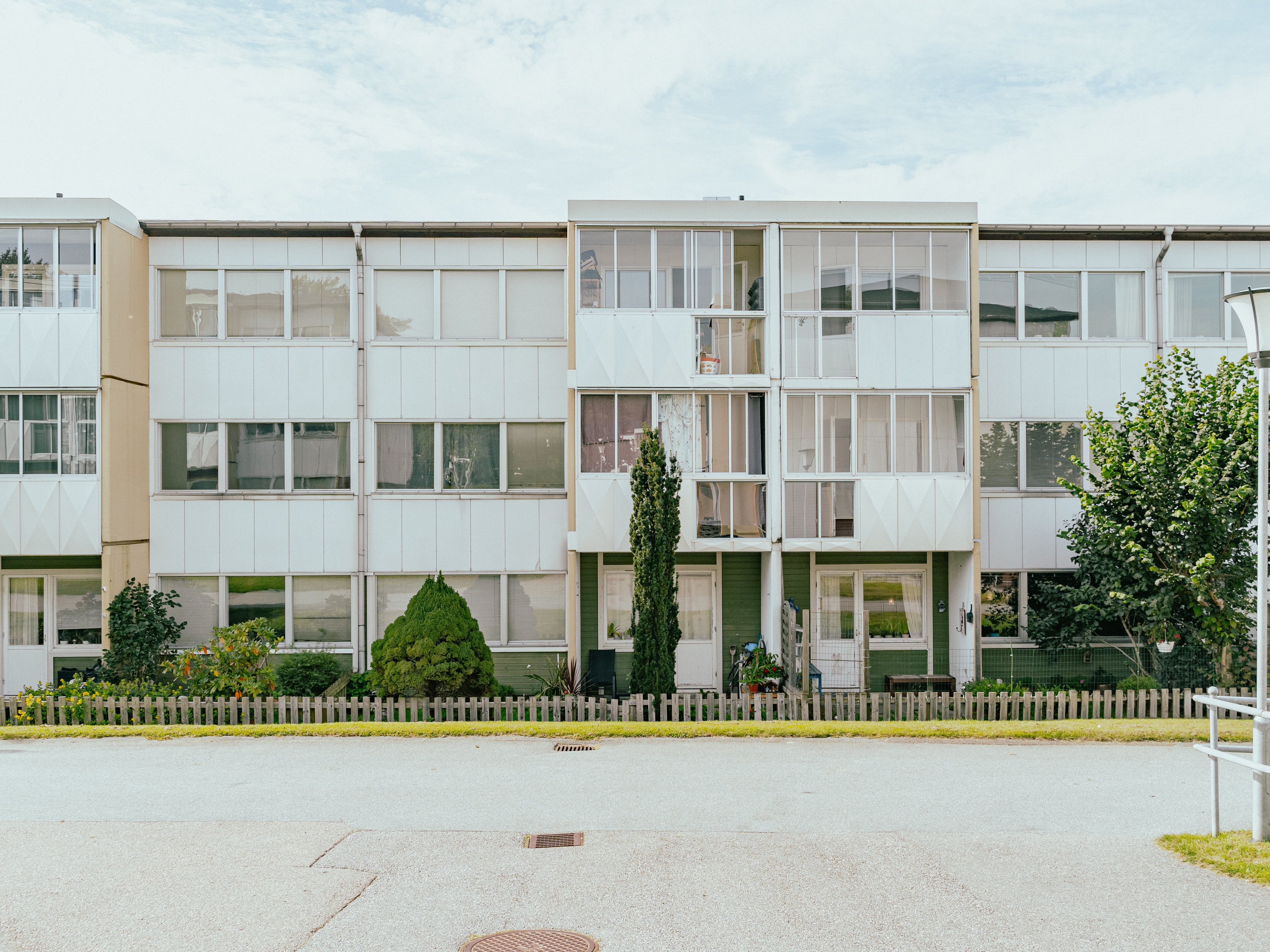 En hyres-länga med uteplatser och en asfalts-yta framför