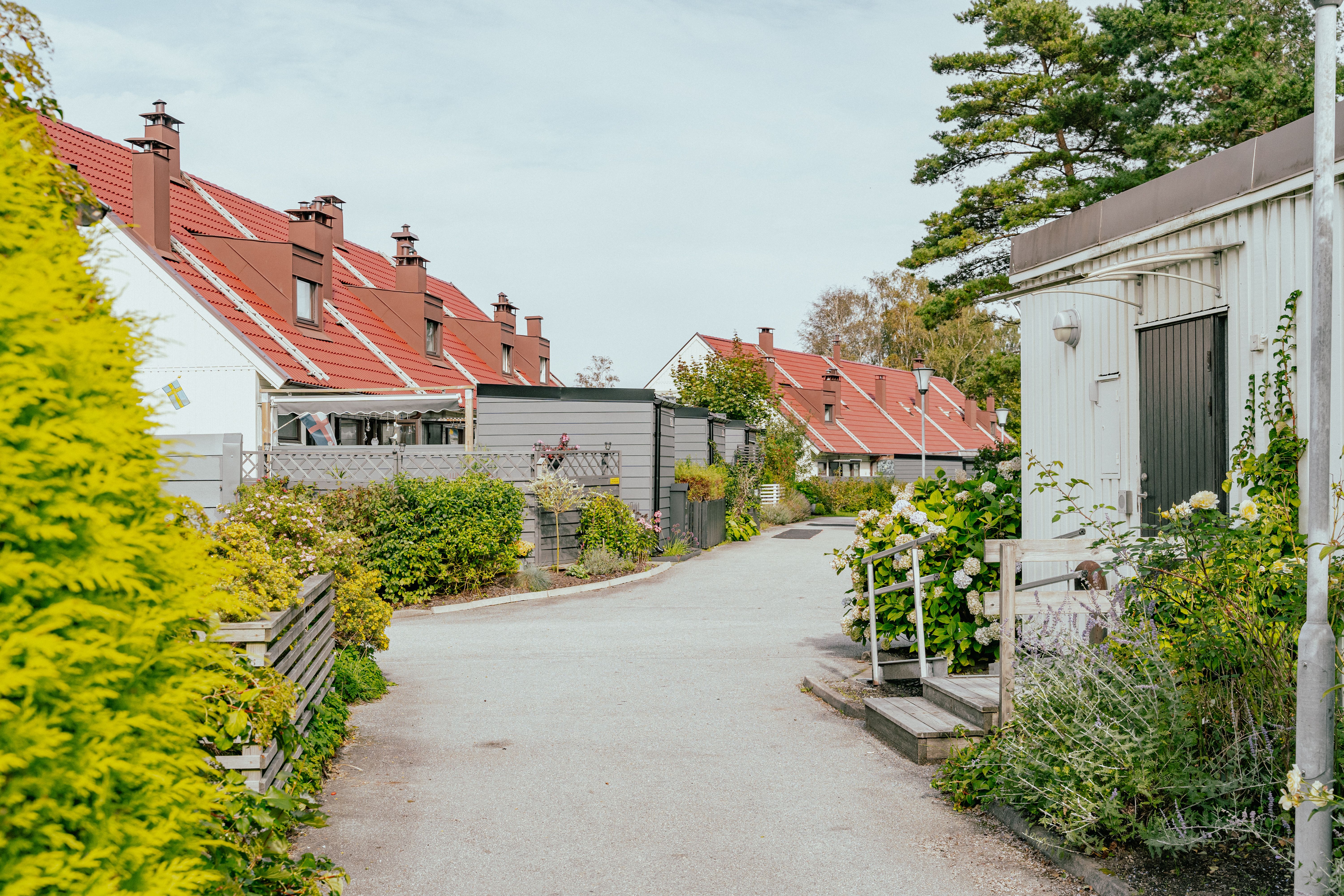 En gågata genom ett radhusområde med planteringar och uteplatser